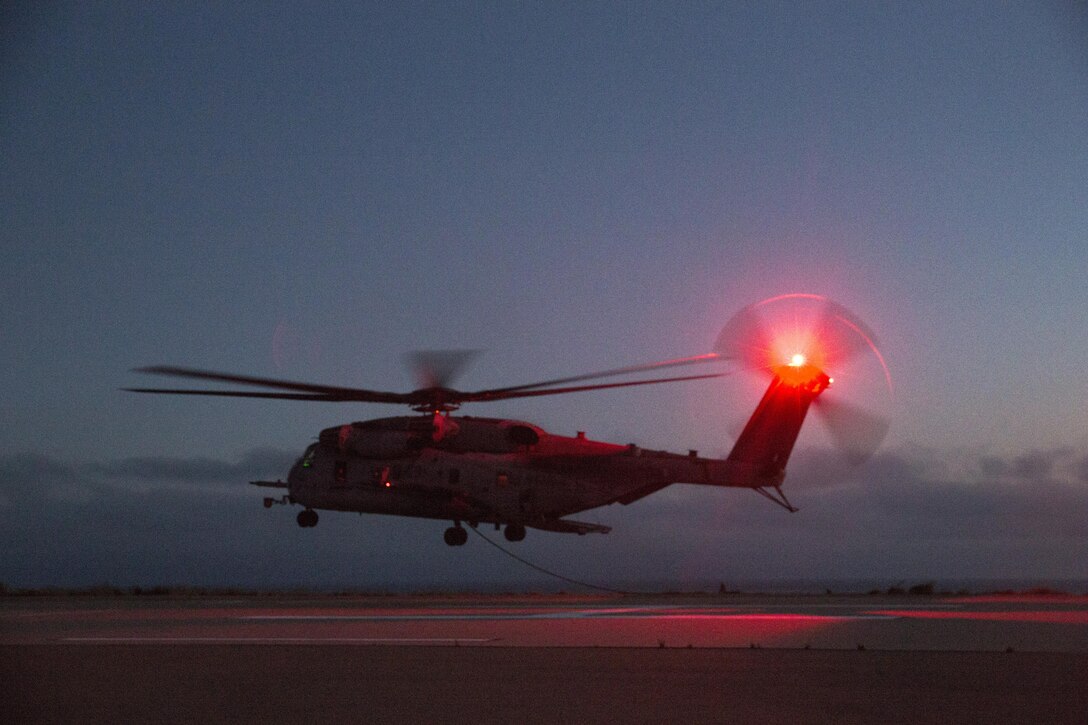 A CH-53E Super Stallion with Marine Heavy Helicopter Squadron (HMH) 466 prepares to receive Marines from Golf Company, Battalion Landing Team 2nd Battalion, 1st Marine Regiment on Marine Corps Base Camp Pendleton, California, July 2. The helicopter’s air crew and the infantry Marines conducted night fast-rope training, a useful skill for both units. (U.S. Marine Corps photo by Sgt. Lillian/Released)