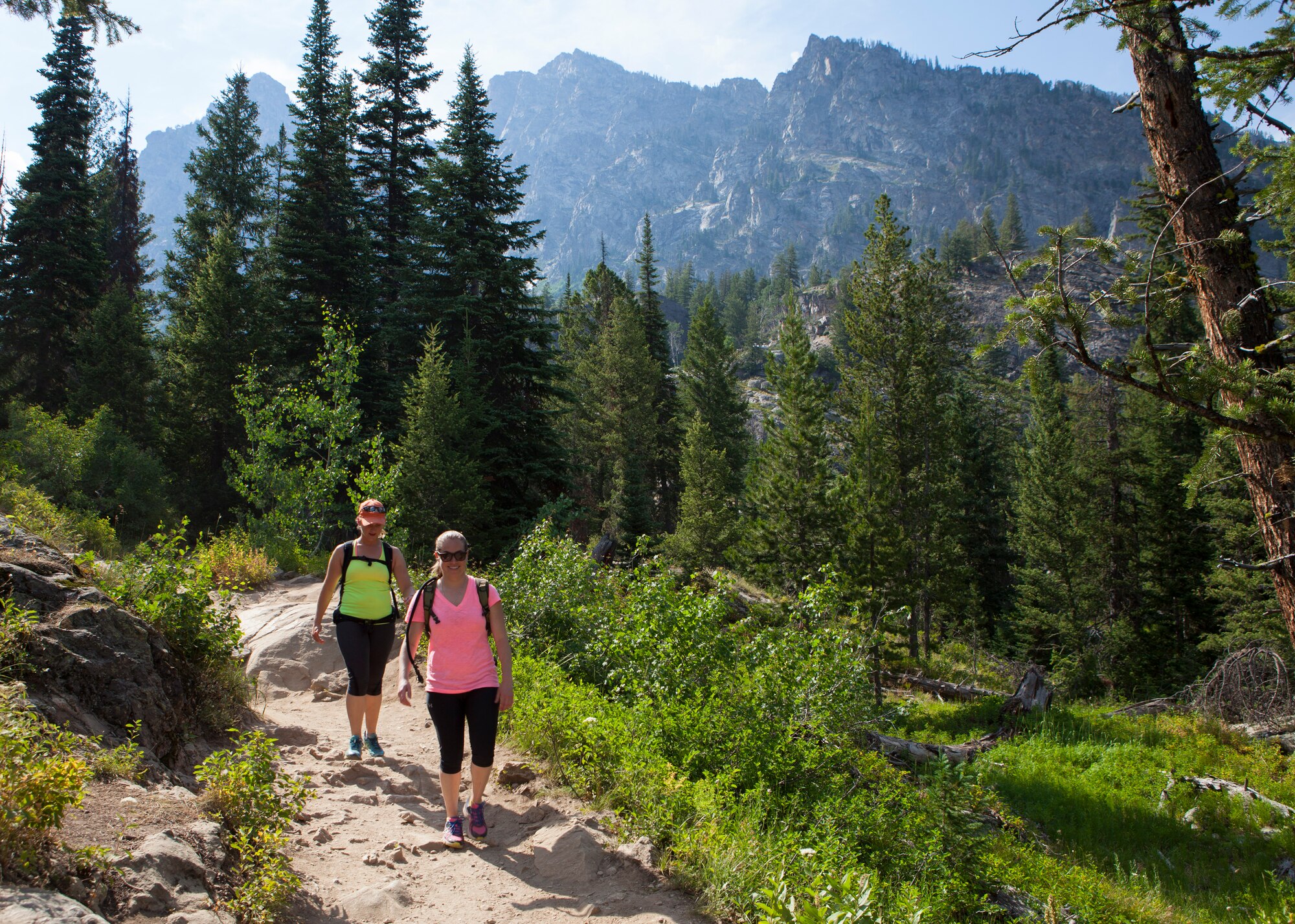 Airman 1st Class Alexis Visser, 90th Munitions Squadron, and Senior Airman Rachel Silverberg, 90th Force Support Squadron, hike the Hidden Falls trail in Grand Teton National Park, Wyo., July 3, 2015. Visser and Silverberg were participants of an F.E. Warren Air Force Base Outdoor Recreation trip that explored the natural attractions of Grand Teton and Yellowstone National Park during the July 4th weekend. (U.S. Air Force photo by Lan Kim)