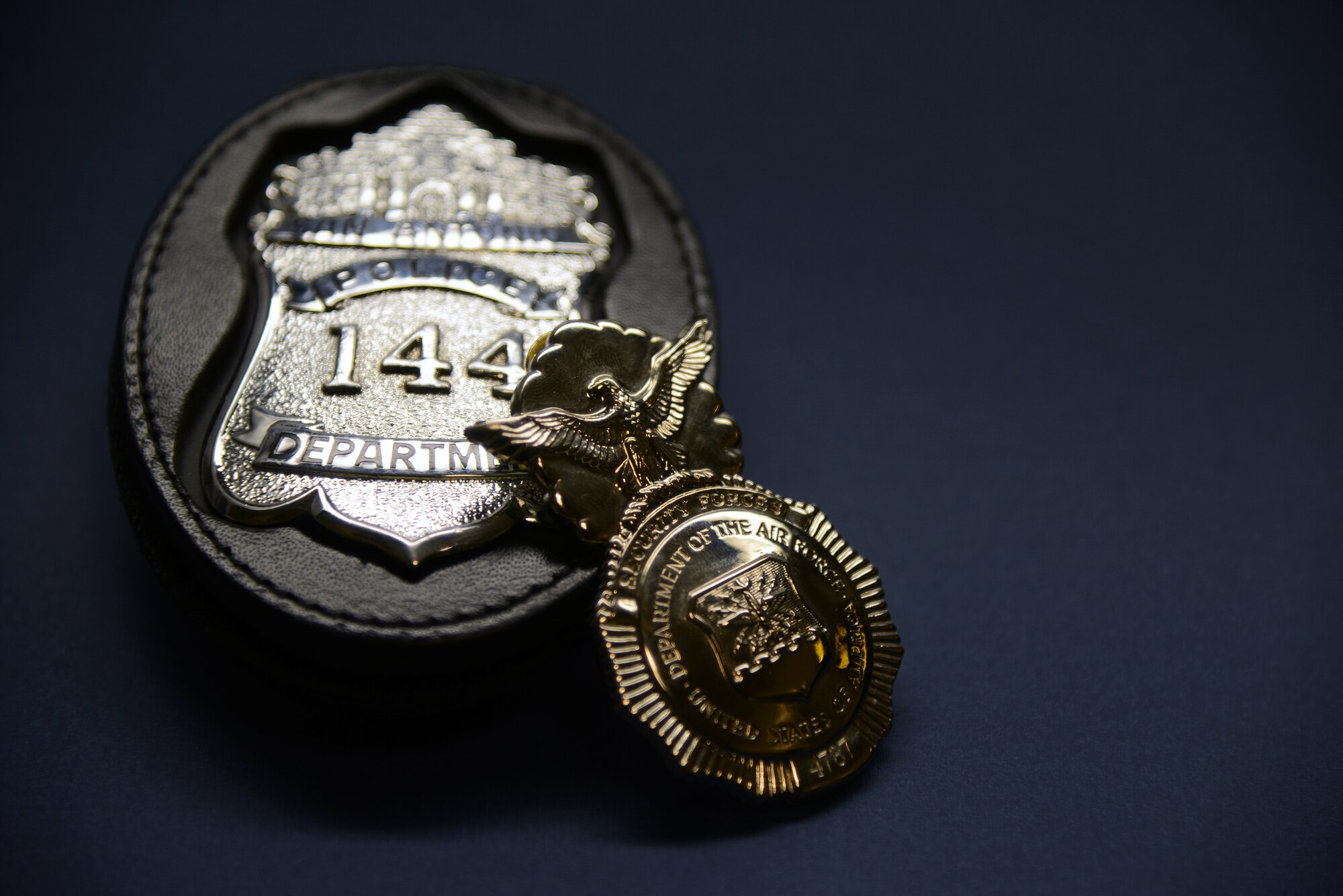 An Air Force Security Police Badge rests against a San Antonio Police Department badge on Laughlin Air Force Base, Texas, July 8, 2015. The badges belong to Christopher Enfinger who serves as a patrol officer assigned to the SAPD Gang Unit, as well as a Master Sgt. assigned to the Air Force Reserves currently stationed at the 47th Security Forces Squadron here. (U.S. Air Force photo by Tech Sgt. Steven R. Doty)(Released)