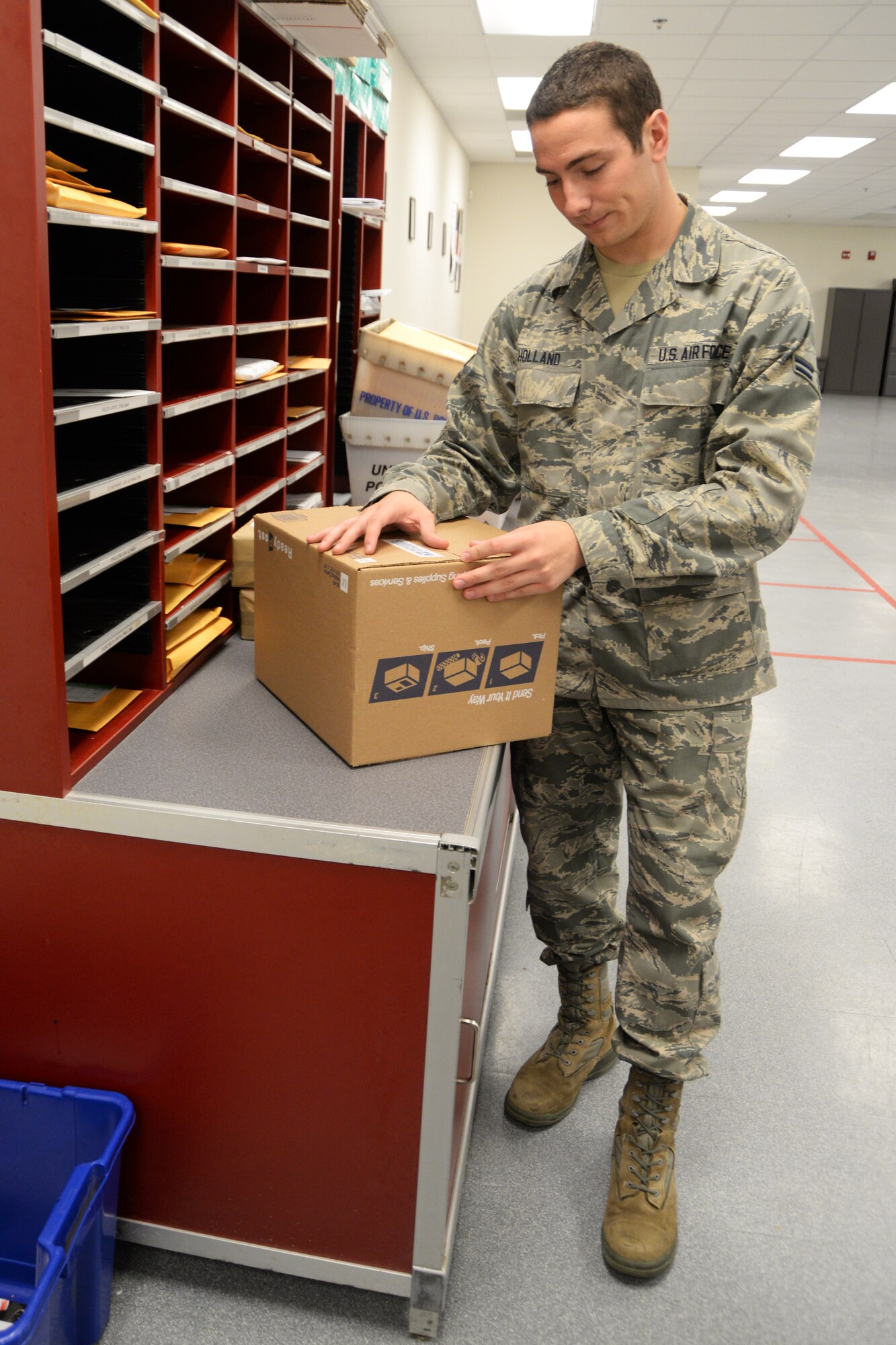 Airman 1st Class Ryan Holland, postal apprentice, prepares a box to make a consolidated package June 24, 2015, Scott Air Force Base, Illinois. Holland was one of the Airmen that helped streamline the program helping save the official mail center money. (U.S. Air Force photo by Airman 1st Class Melissa Estevez)