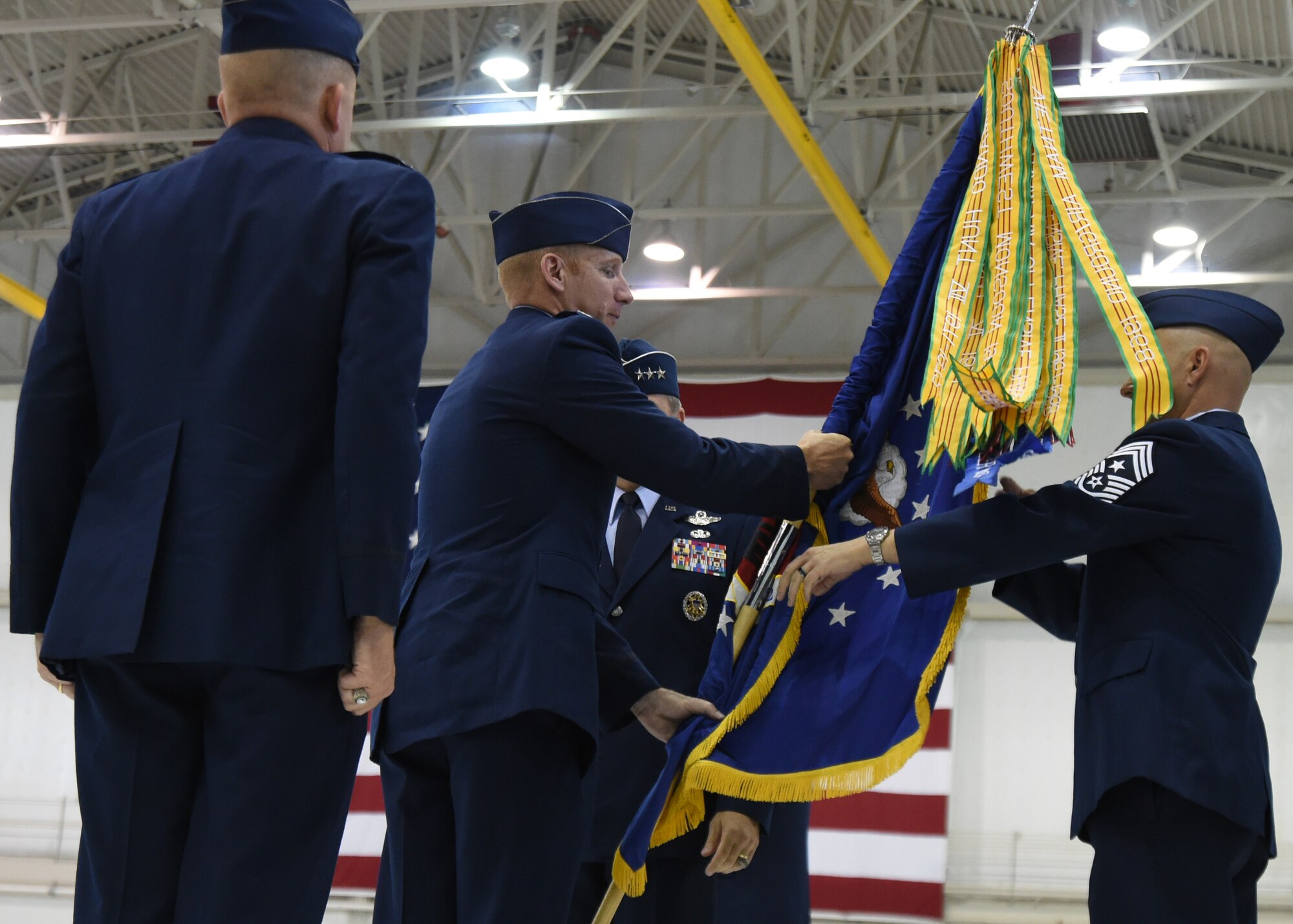 Col. Case Cunningham, 432nd Wing commander, hands the wing guidon to Chief Master Sgt. Michael Ditore, 432nd WG command chief, after taking command from Lt. Gen. Chris Noland, 12th Air Force commander, during a change of command ceremony held on June 29, 2015 at Creech Air Force Base, Nevada. The ceremony indicates to the unit's members the authority of the incoming commander. (U.S. Air Force photo by Tech. Sgt. Shad Eidson/Released)