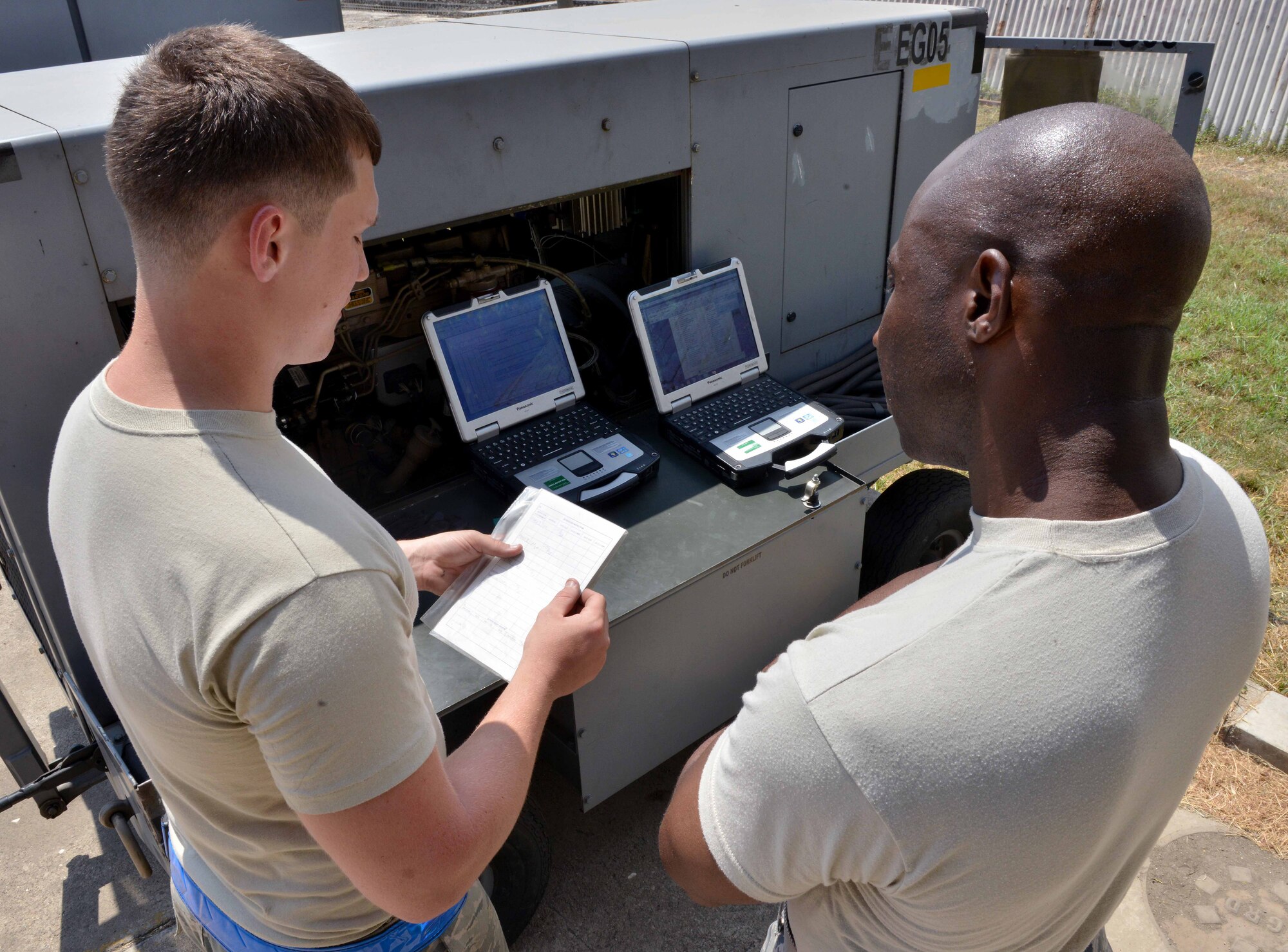 Senior Airman Michael Feagin, 39th Maintenance Squadron Aerospace Ground Equipment journeyman, reviews an equipment service report with Chief Master Sgt. Vegas Clark, 39th Air Base Wing command chief, during a unit visit July 2, 2015, at Incirlik Air Base, Turkey. During his visit, Clark learned how to review service reports and change the oil and service a generator. (U.S. Air Force photo by Senior Airman Michael Battles/Released) 