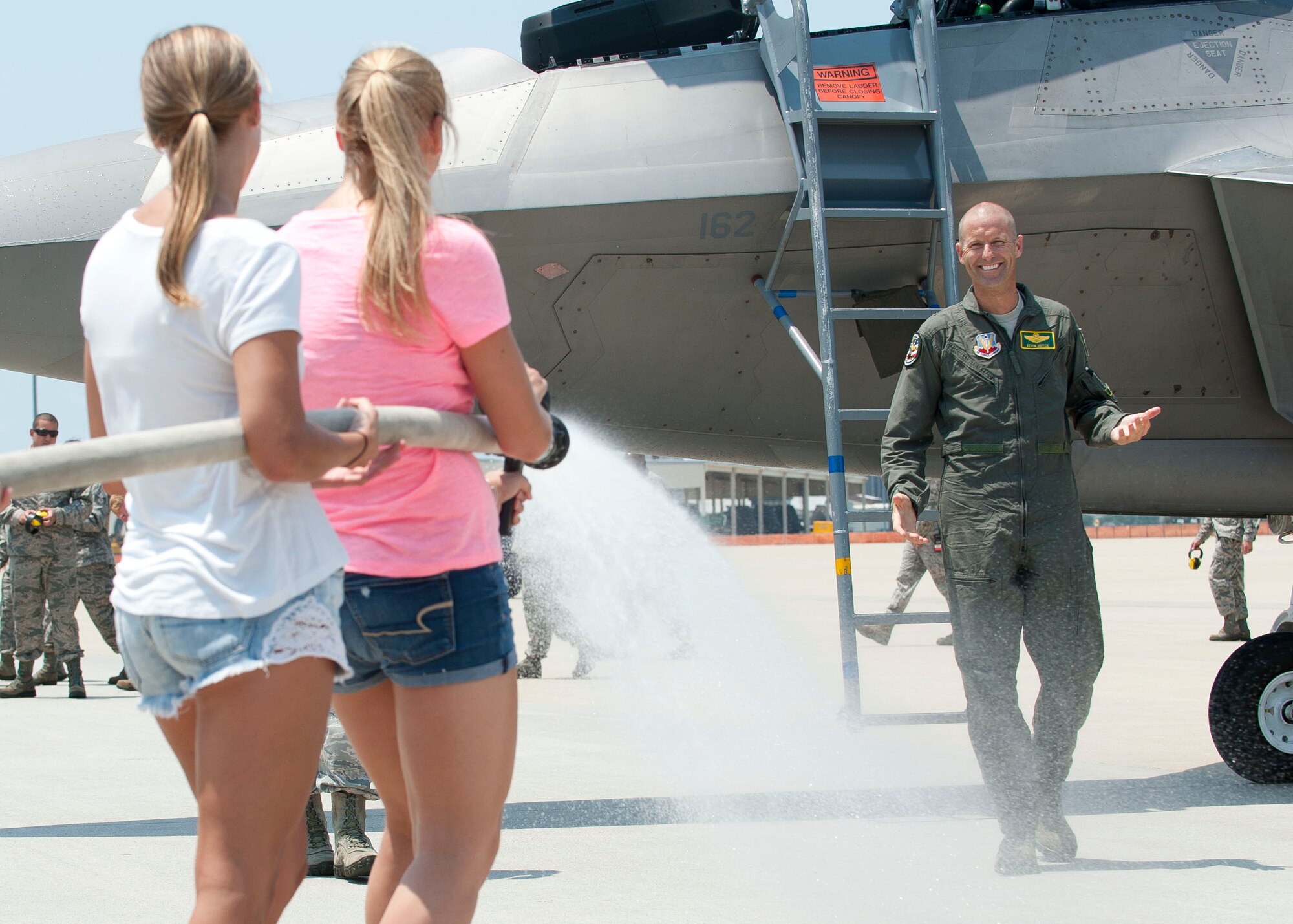 U.S. Air Force Brig. Gen. Kevin Huyck, 1st Fighter Wing commander, is sprayed with a fire hose by his daughters, Meghan and Shanna, after his fini flight at Langley Air Force Base, Va., July 7, 2015. Huyck is a command pilot with more than 3,000 flying hours and 295 combat hours in support of Operation Southern Watch. (U.S. Air Force photo by Staff Sgt. John D. Strong II)