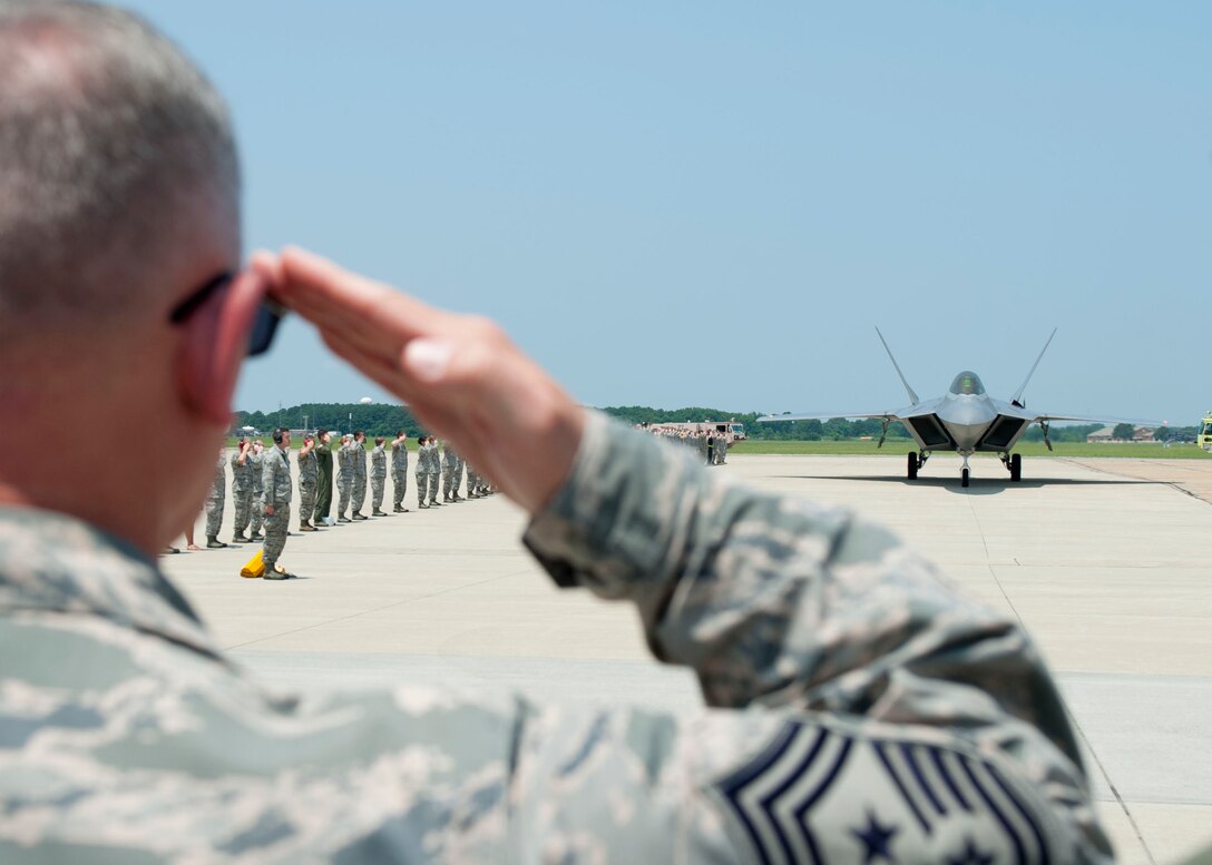 U.S. Air Force Chief Master Sgt. Emmette Bush, 1st Fighter Wing command chief, salutes Brig. Gen. Kevin Huyck, 1st Fighter Wing commander, as he taxis in a F-22A Raptor during his fini flight at Langley Air Force Base, Va., July 7, 2015. As the 1st FW commander, Huyck was responsible for the worldwide rapid deployment and employment of F-22 air dominance fighters in support of combatant commanders. (U.S. Air Force photo by Staff Sgt. John D. Strong II)
