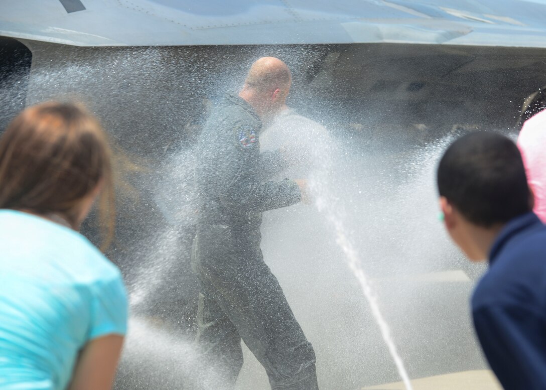 U.S. Air Force Brig. Gen. Kevin Huyck, 1st Fighter Wing commander, gets sprayed with water by family and friends at Langley Air Force Base, Va., July 7, 2015. Huyck received this greeting after his fini flight commemorating his final days as the 1st FW commander. (U.S. Air Force photo by Senior Airman Kimberly Nagle/Released)