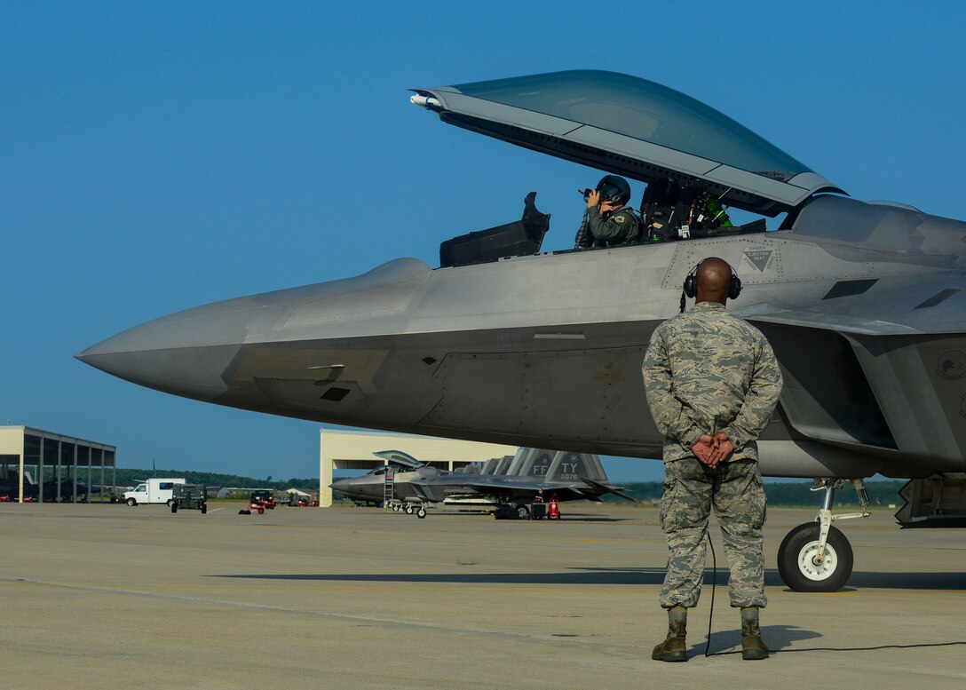 U.S. Air Force Senior Airman Ismael Debarros, 94th Fighter Squadron crew chief, right, assists Brig. Gen. Kevin Huyck, 1st Fighter Wing commander, before the start of his fini flight at Langley Air Force Base, Va., July 7, 2015. Huyck has been the commander for the 1st Fighter Wing for the last two years, commanding more than 1,400 personnel. (U.S. Air Force photo by Senior Airman Kimberly Nagle/Released)