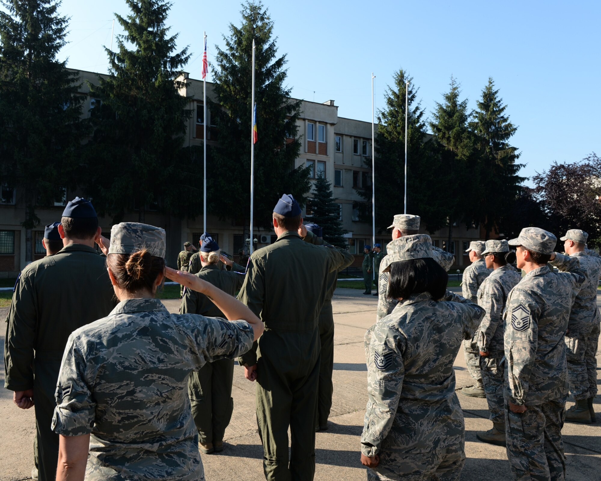 U.S. Air National Guard Airmen from the 123rd Expeditionary Fighter Squadron salute during the playing of the U.S. and Romanian national anthems during an opening ceremony July 6, 2015, at Campia Turzii, Romania. More than 200 Airmen from the 142nd Fighter Wing, Oregon Air National Guard, Portland, Oregon, started training with the Romanian air force as part of a European theater security package of F-15C Eagle fighter aircraft deployed to Romania. (U.S. Air Force photo by Senior Airman Dylan Nuckolls/Released)