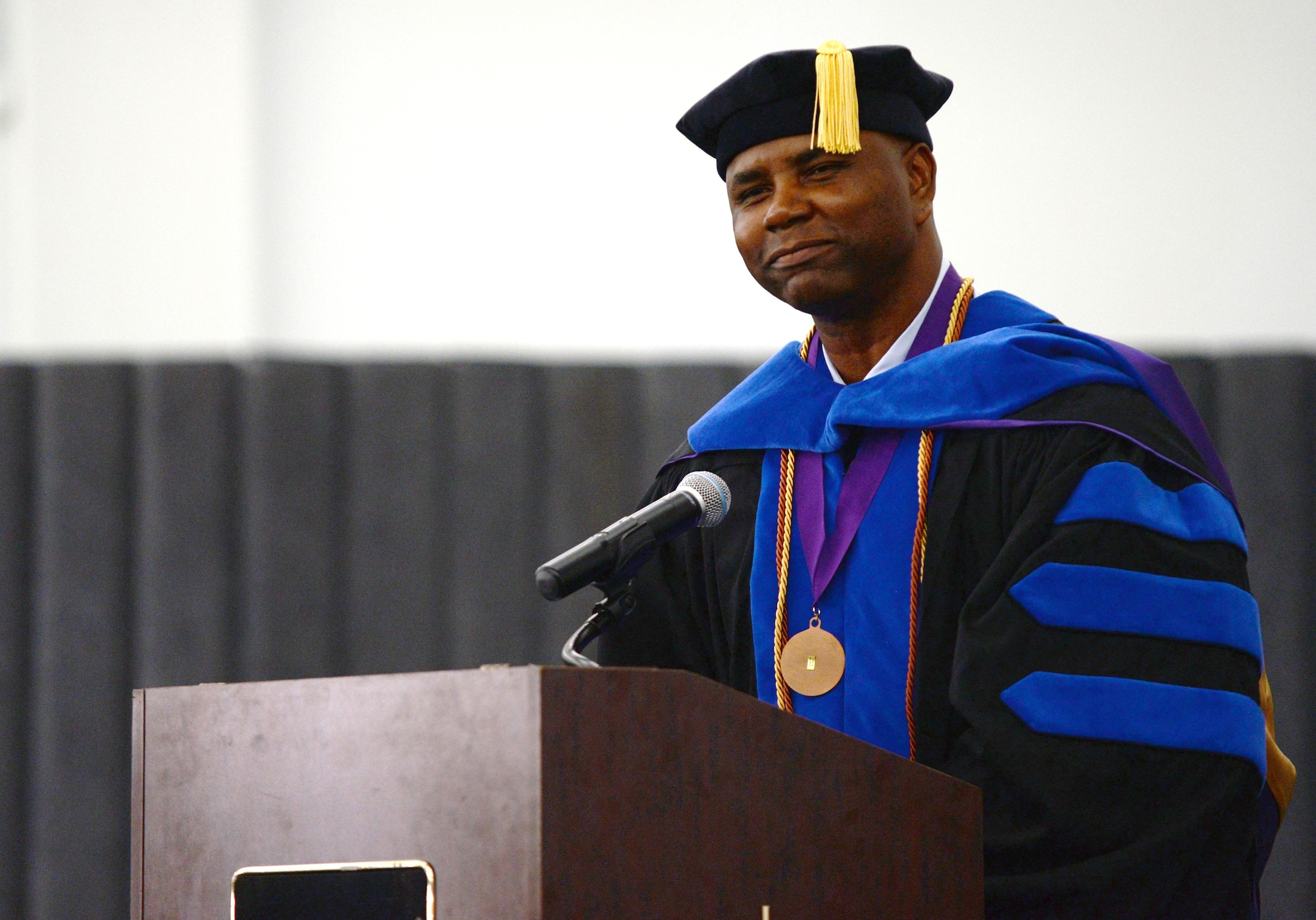 Chief Master Sgt. Marvin Parker, 36th Mission Support Group superintendent, shares anecdotes from his educational journey during a Community College of the Air Force graduation ceremony June 26, 2015, at Andersen Air Force Base, Guam. Parker holds a doctorate in business administration, summa cum laude, and wore his academic regalia to inspire other Airmen to continue their academic journey beyond a two-year degree. (U.S. Air Force photo by Senior Airman Alexander W. Riedel/Released)