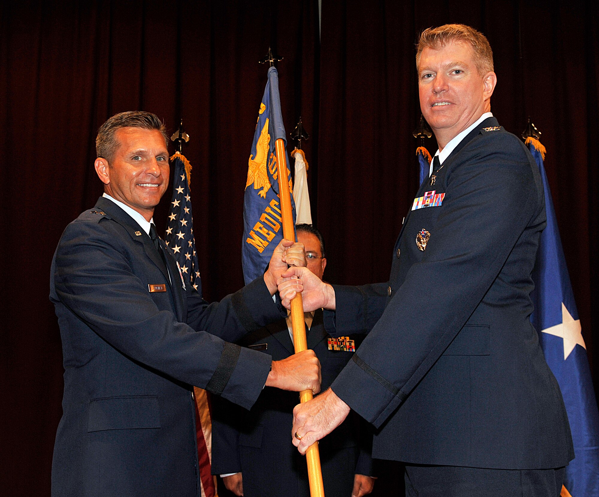 U.S. Air Force Brig. Gen. Barry Cornish, 18th Wing commander, passes the 18th Medical Group guidon to Col. James Lasswell, 18th MDG commander, during the group’s change of command ceremony on Kadena Air Base, Japan, July 9, 2015. The change of command is a traditional military ceremony in which the departing commander relinquishes command to the incoming commander. The 18th Medical Group, the Air Force's largest freestanding ambulatory clinic in terms of assigned personnel, provides extensive medical, dental and support services to Kadena and other Department of Defense beneficiaries living on Okinawa. More than 70 medical and dental providers care for nearly 800 patients every day. (U.S. Air Force photo by Naoto Anazawa)