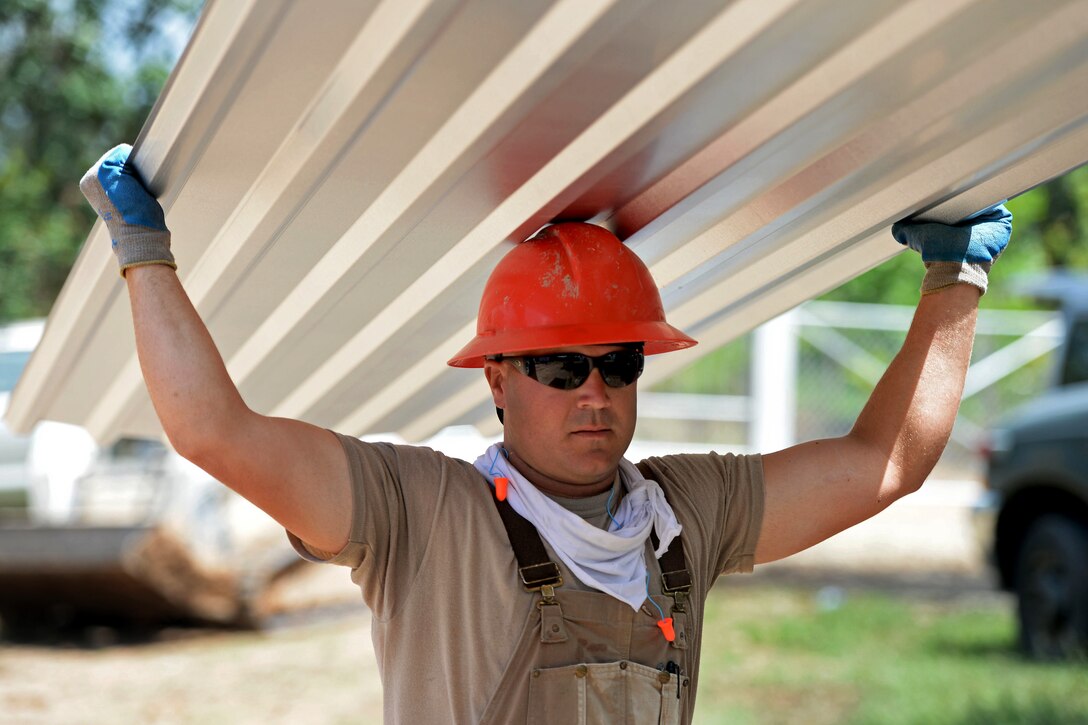 U.S. Air Force Tech. Sgt. Ryan McAllister carries metal roofing at the Gabriela Mistral school construction site in Ocotes Alto, Honduras, June 27, 2015. McAllister is a structural craft lead assigned to the 823rd Expeditionary Red Horse Squadron.
