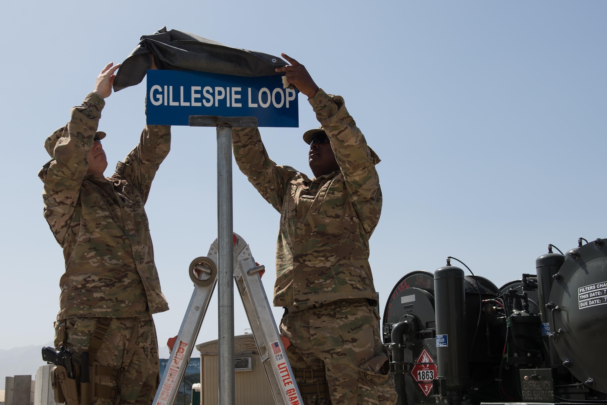 U.S. Air Force Lt. Col. Franklin Livingston, left, 455th Expeditionary Logistics Readiness Squadron commander, and Chief Master Sgt. Troy Ferguson, 455th ELRS fuels manager, unveil the Gillespie Loop sign during the Master Sgt. Randy Gillespie road dedication ceremony at Bagram Airfield, Afghanistan, July 9, 2015. Gillespie was a career fuels specialist who died July 9, 2007, from wounds sustained during small arms fire near Herat, Afghanistan. (U.S. Air Force photo by Tech. Sgt. Joseph Swafford/Released)