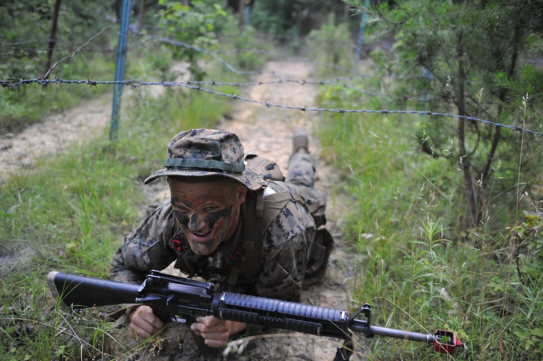 An Officer Candidate negotiates a wire obstacle in the woods of Quantico during a Small Unit Leader Evaluation exercise at Officer Candidate School. The purpose of the exercise is to test individual candidates on their ability to not only lead, but to motivate and confidently accomplish the mission with their unit while in a chaotic environment.