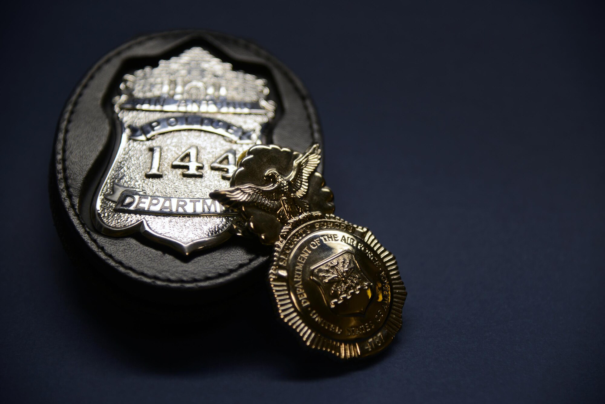 An Air Force Security Police Badge rests against a San Antonio Police Department badge on Laughlin Air Force Base, Texas, July 8, 2015. The badges belong to Christopher Enfinger who serves as a patrol officer assigned to the SAPD Gang Unit, as well as a Master Sgt. assigned to the Air Force Reserves currently stationed at the 47th Security Forces Squadron here. (U.S. Air Force photo by Tech Sgt. Steven R. Doty)