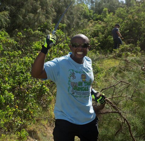 Gunnery Sgt. Jimi Khamisi, a section leader with Marine Wing Support Squadron 374, brandishes his saw after taking down a large branch from an invasive species of plant June 13.