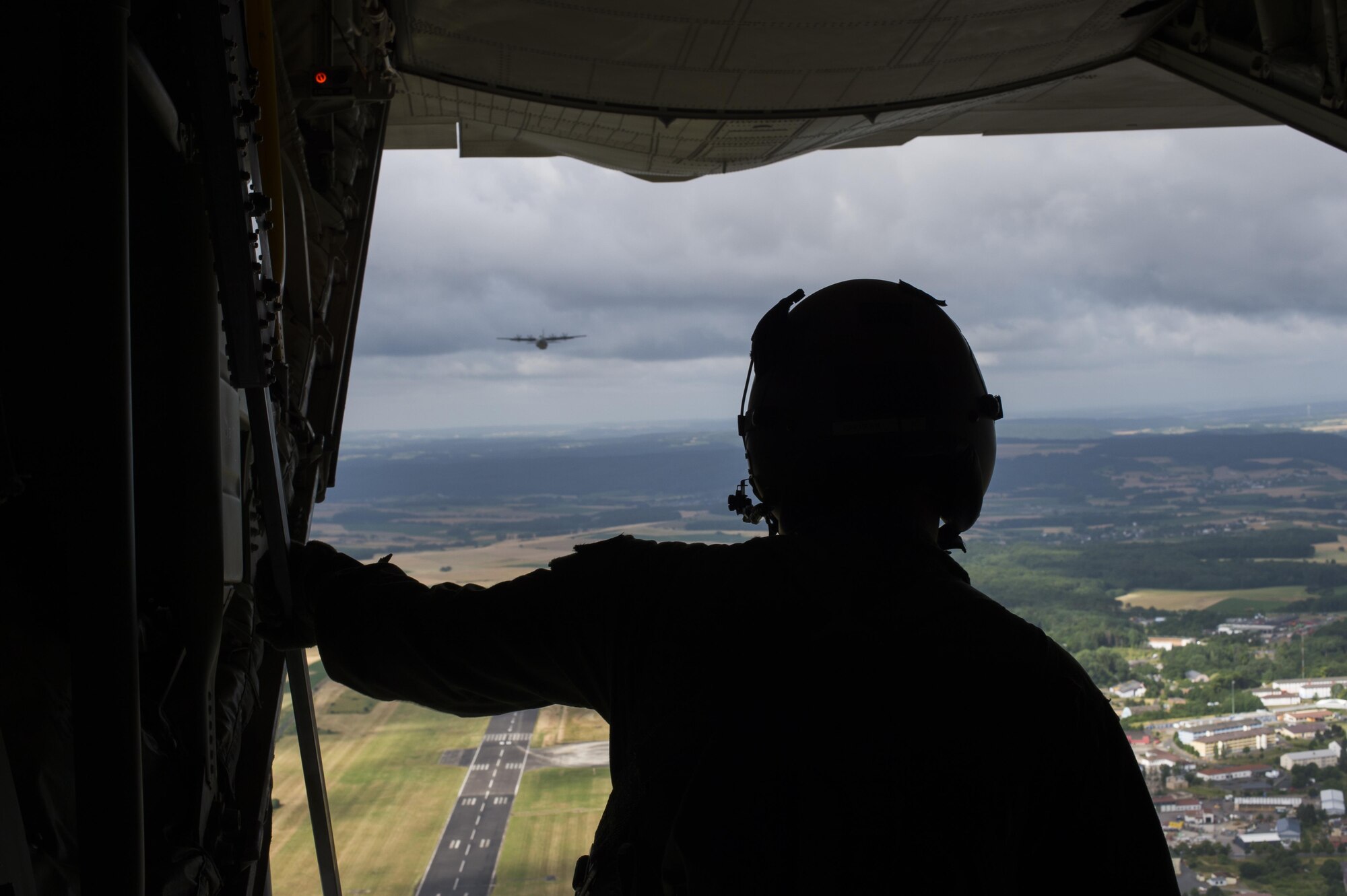 Airman 1st Class Austin Lilly, a 37th Airlift Squadron loadmaster, looks out the back of a C-130J Super Hercules, ensuring paratroopers can safely exit the aircraft during International Jump Week, July 8, 2015, at Ramstein Air Base, Germany. International Jump Week is an annual event that gives paratroopers the opportunity to practice high altitude, low opening and static line jumps. Pilots, loadmasters and parachute riggers were also able to train during the week. (U.S. Air Force photo/Senior Airman Damon Kasberg)