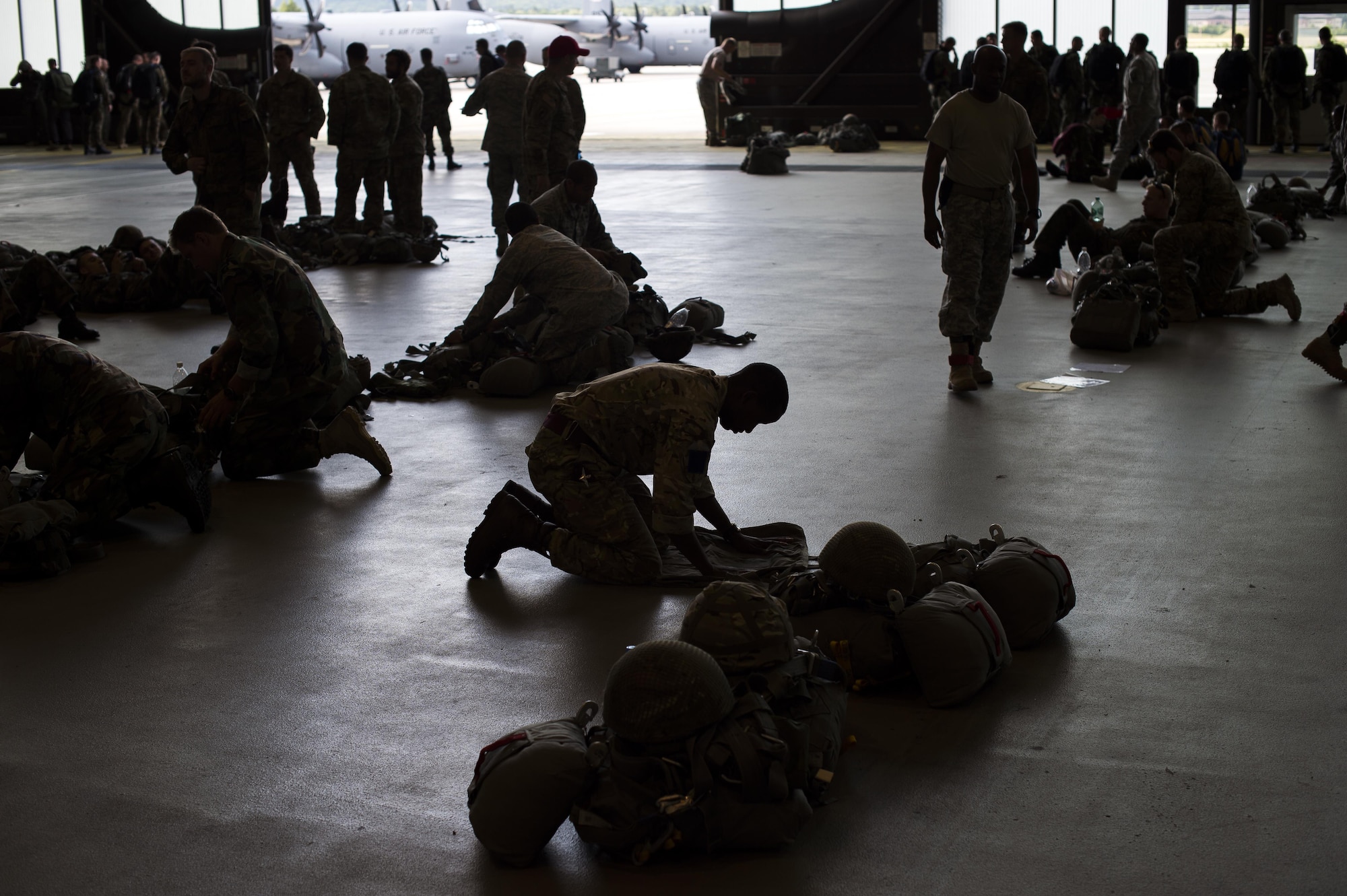 Service members pack parachutes prior to jumping during International Jump Week, July 8, 2015, at Ramstein Air Base, Germany. International Jump Week is an annual event providing paratroopers the opportunity to practice high altitude, low opening and static line jumps. Pilots, loadmasters and parachute riggers were also able to train during the week. Supporting units at the drop zone included U.S. Air Force and Army personnel, air traffic controllers, and medical teams. (U.S. Air Force photo/Senior Airman Damon Kasberg)