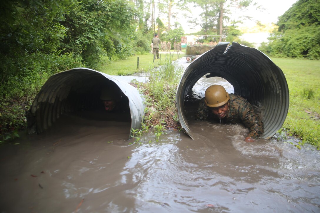 Marines with Service Company, Headquarters Regiment, 2nd Marine Logistics Group crawl through tunnels of muddy water during an endurance course aboard Camp Lejeune, N.C., July 1, 2015. Marines navigated through obstacles to promote and build unit camaraderie while they worked together to progress through swampy terrain. (U.S. Marine Corps photo by Lance Cpl. Aaron K. Fiala/released)