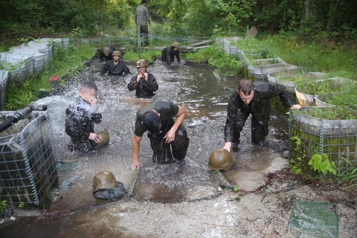 Marines with Service Company, Headquarters Regiment, 2nd Marine Logistics Group wash off after completing the final obstacle during an endurance course aboard Camp Lejeune, N.C., July 1, 2015. Marines navigated through obstacles to promote and build unit camaraderie while they worked together to progress through swampy terrain. (U.S. Marine Corps photo by Lance Cpl. Aaron K. Fiala/released)