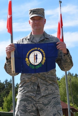 Senior Airman Steven Adkins, a broadcast journalist assigned to American Forces Network, Spangdahlem Air Base, Germany, proudly displays his state flag June 7, 2015, during an assignment for exercise Saber Strike 15 in the Drawsko Pomorskie Training Area in Poland. The flag was given to Adkins by his grandfather, a retired Air Force veteran, who kept a ledger of every location he traveled to with the flag during his last six years in the service, and then gave it to Adkins to carry on the tradition. (U.S. Army photo/Sgt. Brandon Anderson)