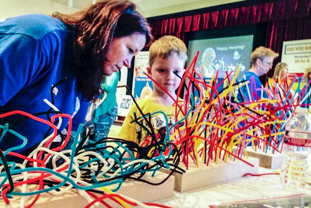 Dr. Kathy Gates, Hearing Center of Excellence (HCE) prevention lead, demonstrates with pipe cleaners how hair cells are damaged by loud noises, to Braxton, 5. son of Tanisha Hammill, HCE senior research coordinator, at a local museum, March 29, 2015. (Courtesy photo)