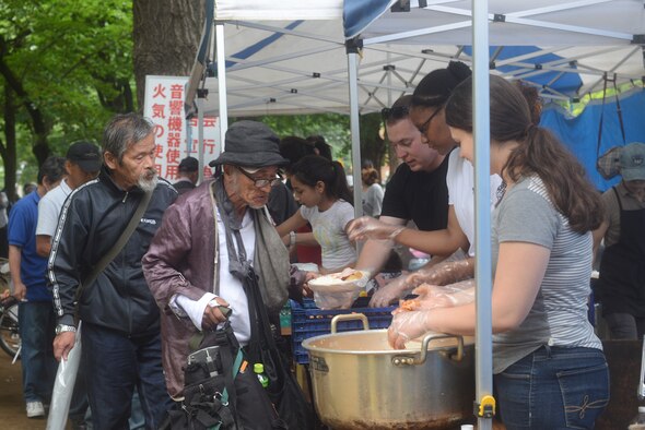 Members from Yokota Air Base, Japan, and members of a local church serve food to the homeless at Ueno Park, Tokyo Japan, June 26, 2015. The base chapel has received multiple commendations, including the Zenko-Kai award, for their participation in homeless outreach events. (U.S. Air Force photo by Airman 1st Class David C. Danford/Released)