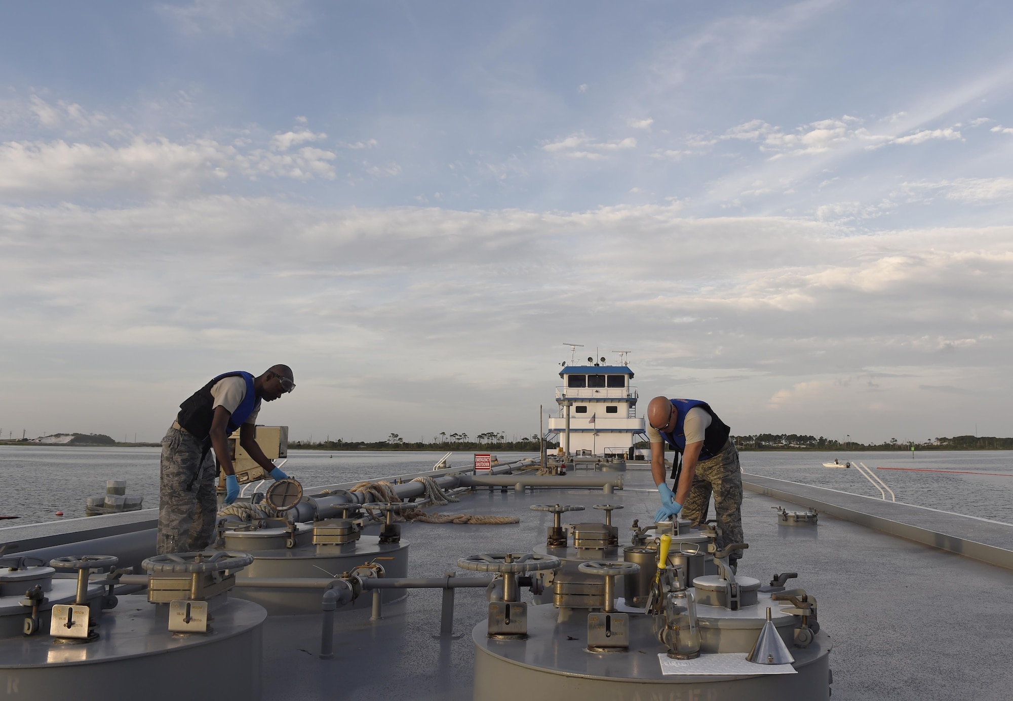 Staff Sgt. Anthony McCullan and Senior Airman Johnathan Morgan, 1st Special Operations Logistics Readiness Squadron fuel laboratory technicians, take samples from a fuel delivery barge at Hurlburt Field, Fla., June 25, 2015. For every fuel delivery, fuels Airmen conduct quality control tests to ensure the Air force is receiving the proper grade and amount of fuel. (U.S. Air Force photo /Airman Kai White/Released)