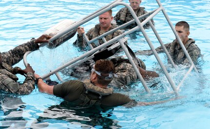 (Front) Tech. Sgt. Justin McCaffrey, the Joint Task Force – Bravo personnel recovery noncommissioned officer in charge, conducts underwater egress training with members of the 1 – 228th Aviation Regiment July 9, 2015, at Soto Cano Air Base, Honduras. The training teaches the crewmembers what steps to take in the event of a water evacuation from a helicopter. (U.S. Air Force photo by Staff Sgt. Jessica Condit) 