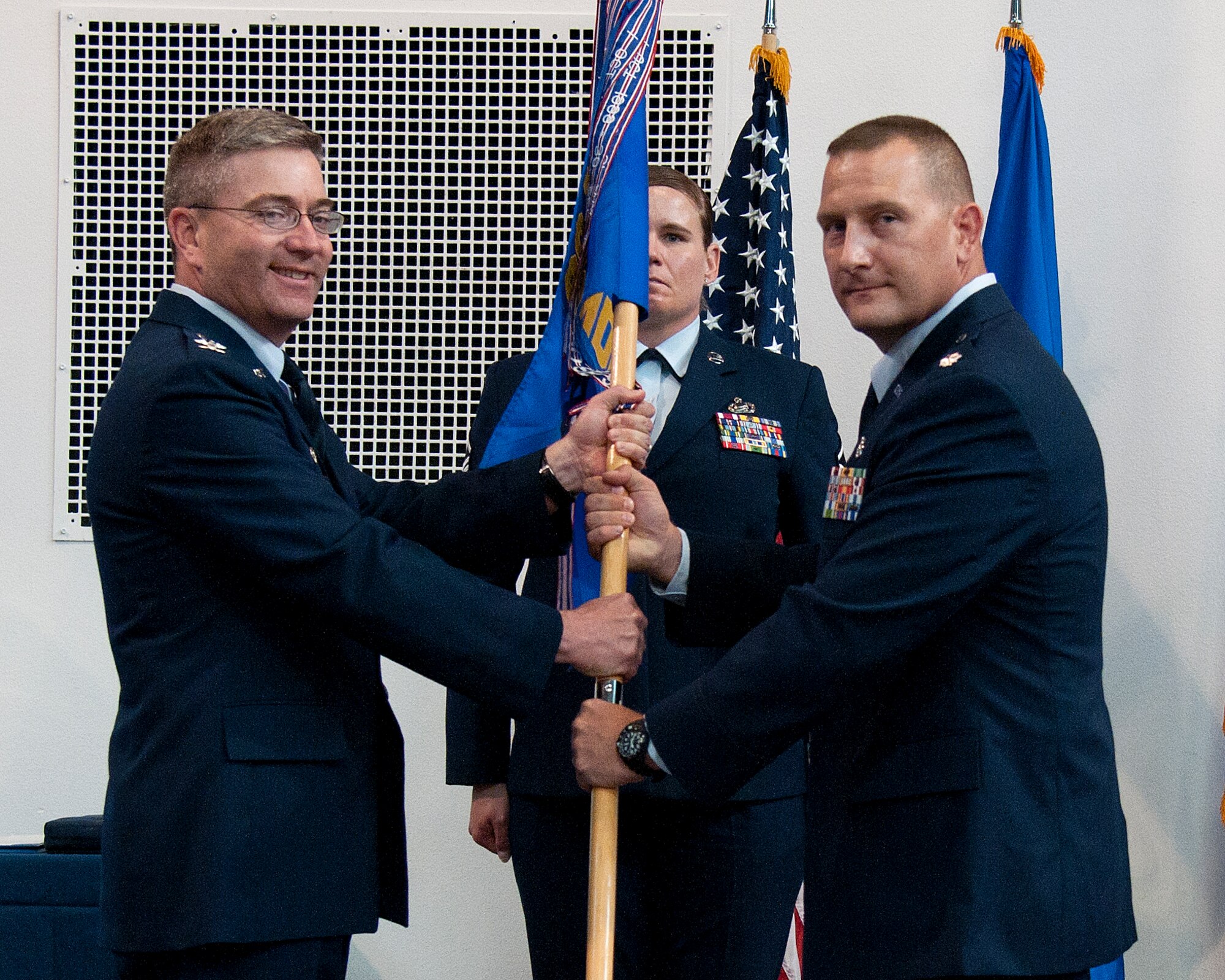 Col. Hans Ritschard, 90th Medical Group commander, passes the guidon to Lt. Col. John Modra, 90th Medical Operation Squadron commander, during the 90th MDOS change of command ceremony July 10, 2015, as Master Sgt. Annamarie Forgit, 90th MDG first sergeant, stands in the background in the Fall Hall Community Center on F.E. Warren Air Force Base, Wyo. The ceremony signified the transition of command from Lt. Col. Penny Spaid to Modra. (U.S. Air Force photo by Airman 1st Class Malcolm Mayfield)