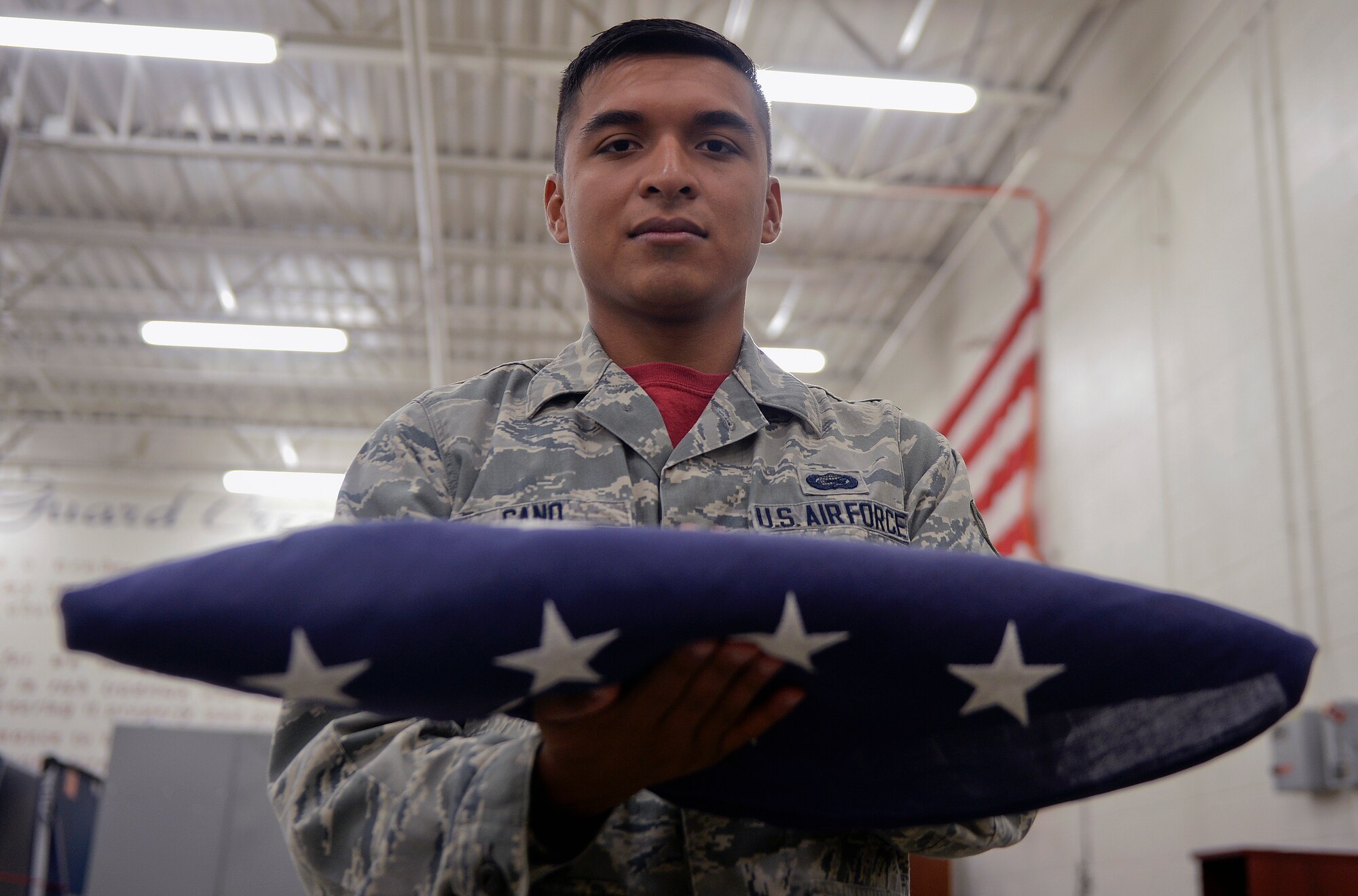 Senior Airman James Cano, 22nd Force Support Squadron honor guard, simulates giving a flag to the family of a fallen service member July 10, 2015, at McConnell Air Force Base, Kan. Flag folding can be a part of several different ceremonies and are treated with utmost respect by the Airmen conducting the fold. (U.S. Air Force photo by Senior Airman Colby L. Hardin)