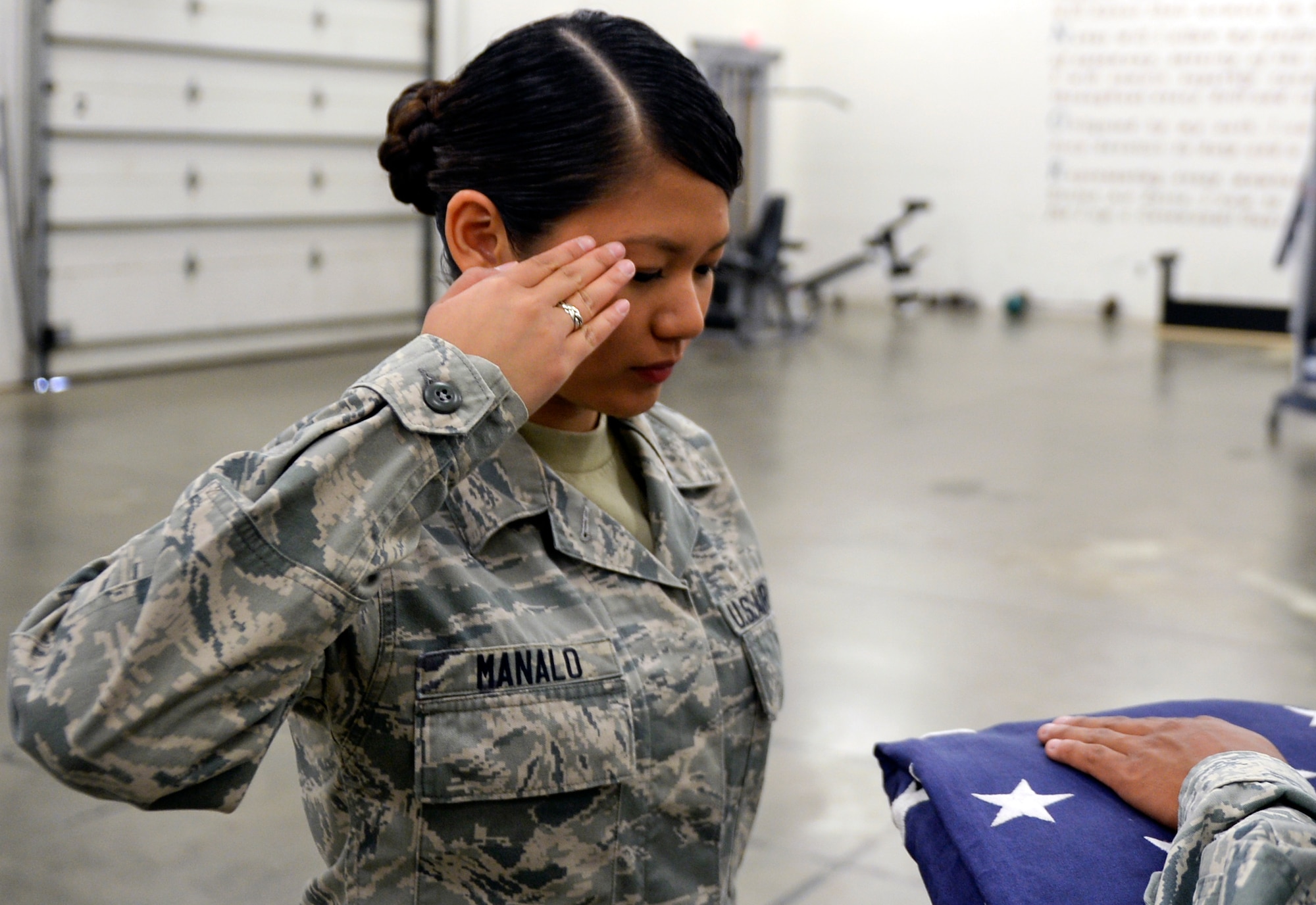 Airman 1st Class Vanessa Manalo, 22nd Force Support Squadron honor guardsman, salutes the U.S. flag during a two-man flag fold July 10, 2015, at McConnell Air Force Base, Kan. After the flag transfers hands, the member sending the flag off renders a salute as a sign as respect. (U.S. Air Force photo by Senior Airman Colby L. Hardin)