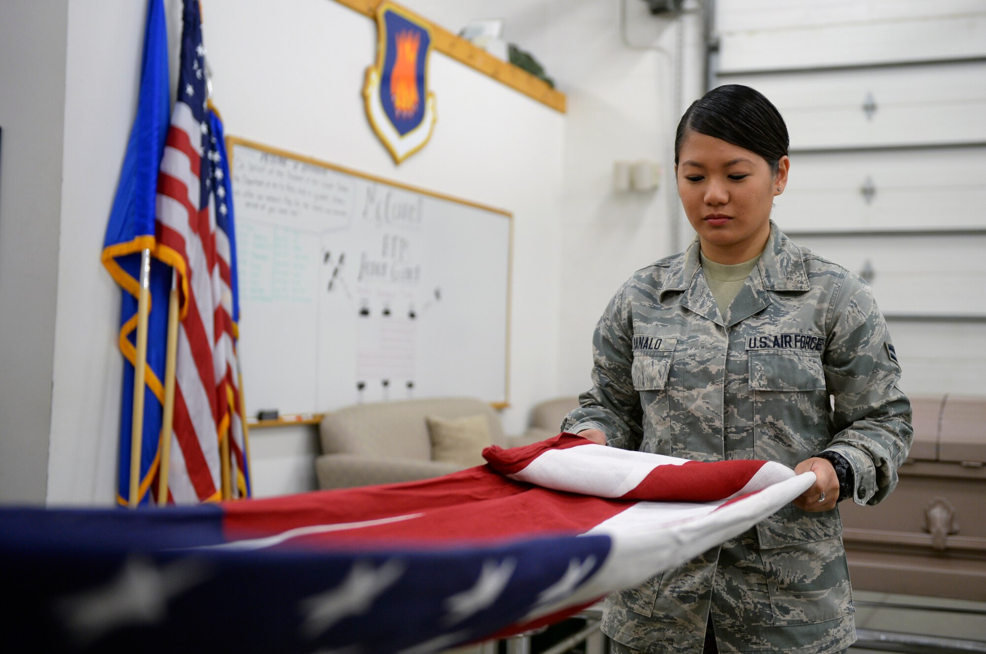 Airman 1st Class Vanessa Manalo, 22nd Force Support Squadron honor guardmen, unfolds a U.S. flag July 10, 2015, at McConnell Air Force Base, Kan. Unfolding the flag is one of the first steps in a two-man flag fold. (U.S. Air Force photo by Senior Airman Colby L. Hardin)