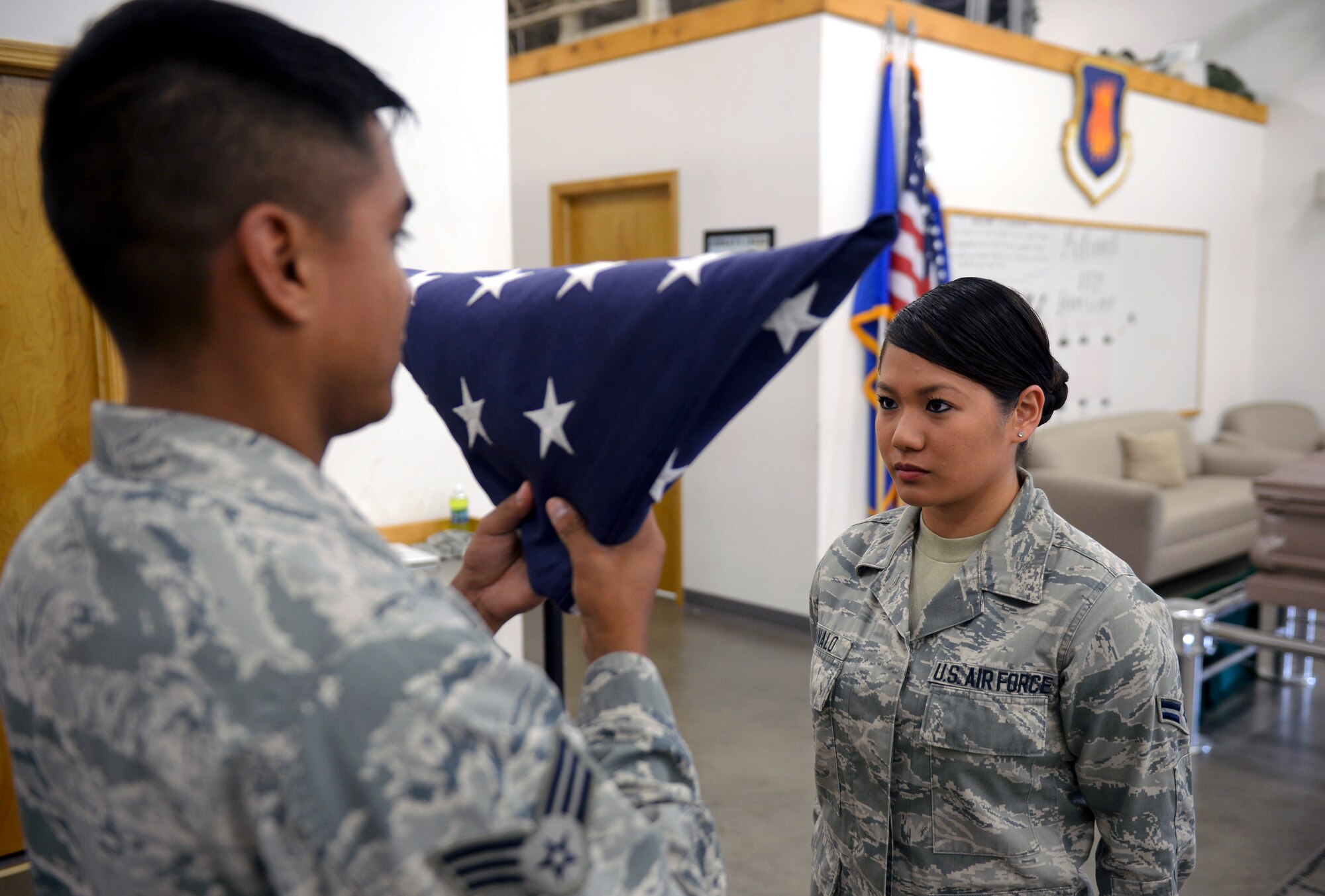 Senior Airman James Cano, left, and Airman 1st Class Vanessa Manalo, 22nd Force Support Squadron honor guardsmen, practice a two-man flag fold July 10, 2015, at McConnell Air Force Base, Kan. The honor guard trains eight hours a day in order to achieve their goal of perfection. (U.S. Air Force photo by Senior Airman Colby L. Hardin)