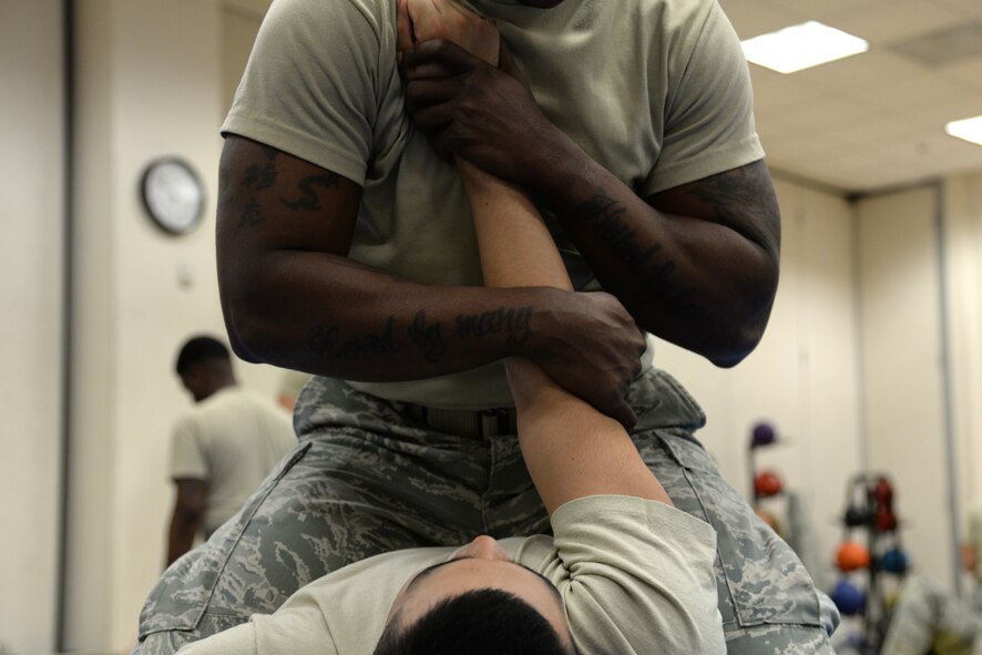 Staff Sgt. Darius Creasey, 47th Security Forces Squadron Alpha Flight chief, begins to apply an ‘arm bar’ on Senior Airman Richard Heshmaty, 47th SFS Base Defense Operations Center patrolman, in Losano Fitness Center on Laughlin Air Force Base, Texas, July 10, 2015. Combatives training is provided annually to security forces personnel to integrate combative training with modern control procedures, teaching the principles of restraint so as to prevent the use of unnecessary force in the handling of military personnel and/or prisoners. (U.S. Air Force photo by Airman 1st Class Brandon May)(Released)