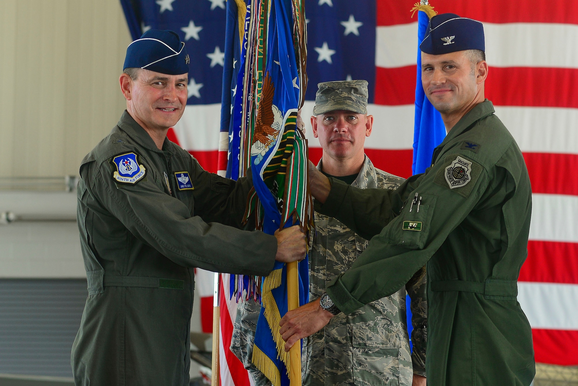 From left, U.S. Air Force Maj. Gen. H.D. Polumbo Jr., 9th Air Force commander, Chief Master Sgt. Emmette Bush, 1st Fighter Wing command chief, and Col. Pete Fesler, 1st FW incoming commander, pass a guidon during the 1st FW change of command ceremony at Langley Air Force Base, Va., July 10, 2015. After the passing of the guidon, Fesler assumed command of the wing after serving at the Pentagon as the Chief of Staff for the Joint Staff. (U.S. Air Force photo by Senior Airman Kimberly Nagle/Released)  