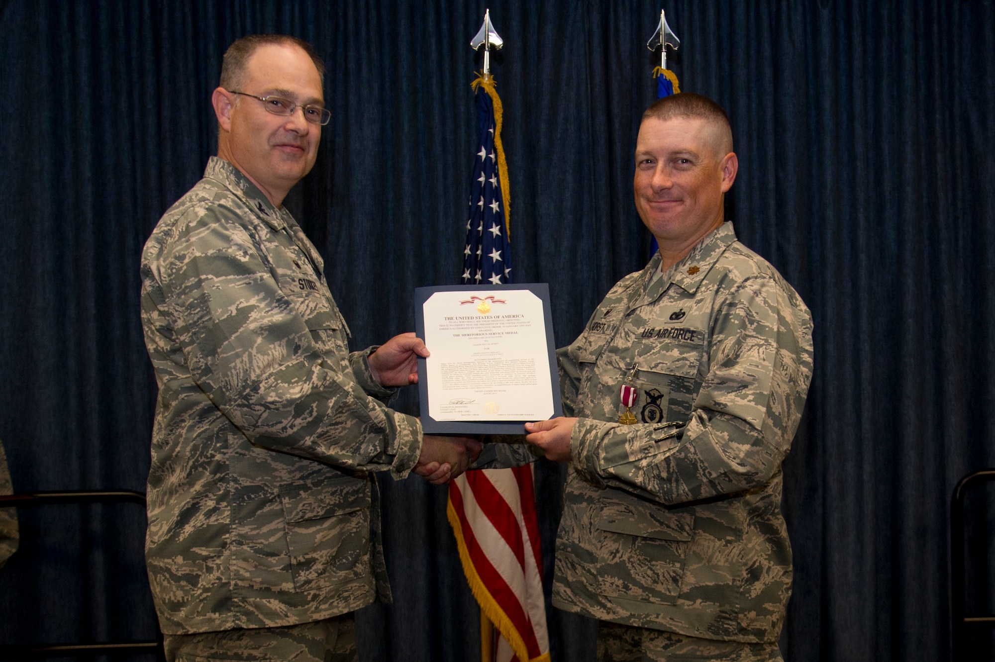 Col. David Stookey, 92nd Mission Support Group commander, presents the Meritorious Service Medal certificate to Maj. Eric M. Horst, former 92nd Security Forces Squadron commander, during the 92nd SFS change of command, July 10, 2015, at Fairchild Air Force Base, Wash. The Meritorious Service Medal is an award given for outstanding meritorious achievement. (U.S. Air Force photo/Airman 1st Class Nicolo J. Daniello)
