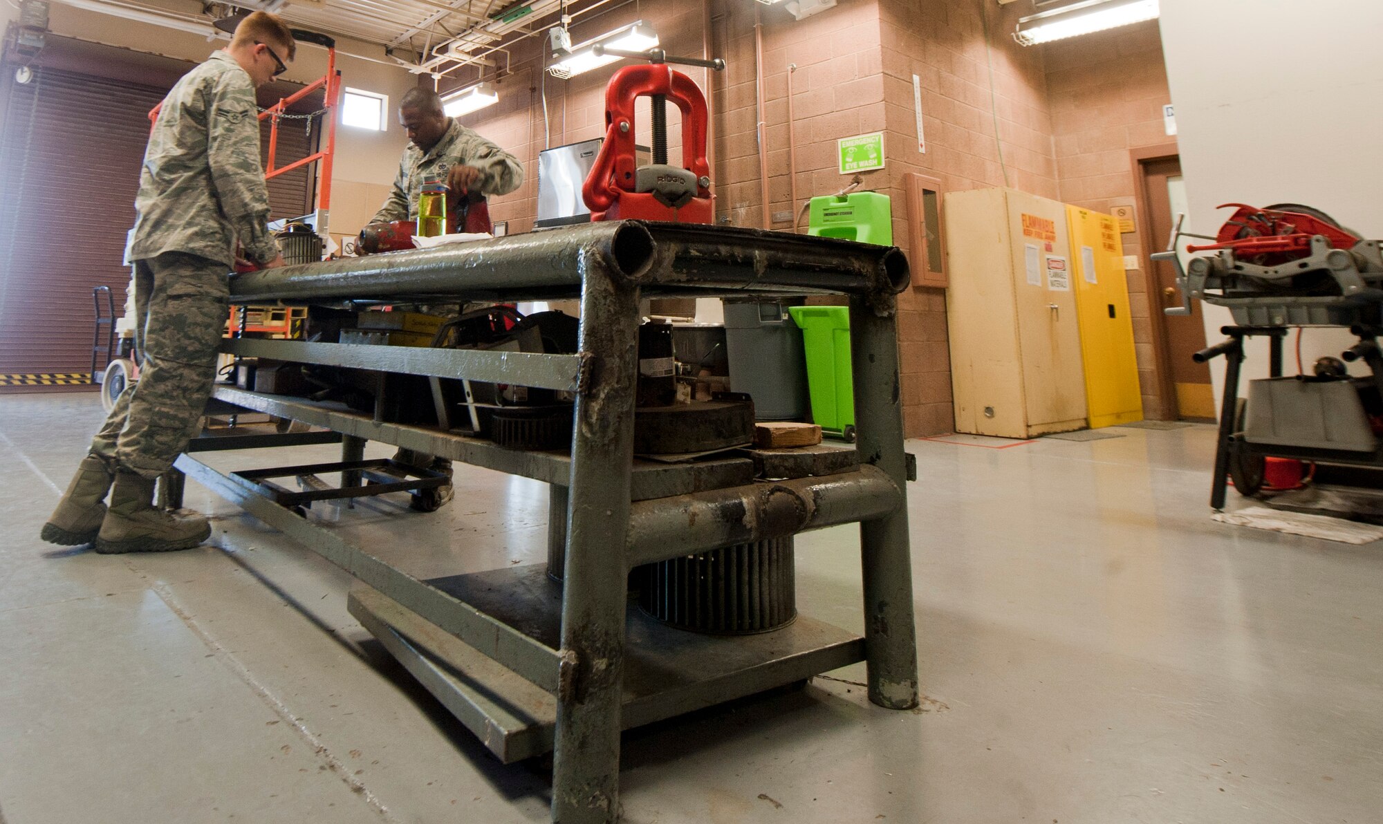 Tech. Sgt. Michael Anderson, right, and Airman 1st Class Zachery Hatfield, both technicians assigned to the 99th Civil Engineer Squadron heating, ventilation, air conditioning and refrigeration shop, work together to take apart a fan at the 99th CES compound on Nellis Air Force Base, Nev., July 8, 2015. The HVAC/R flight maintains approximately 2.5 billion British thermal unit physical plants on base. (U.S. Air Force photo by Airman 1st Class Mikaley Towle) 