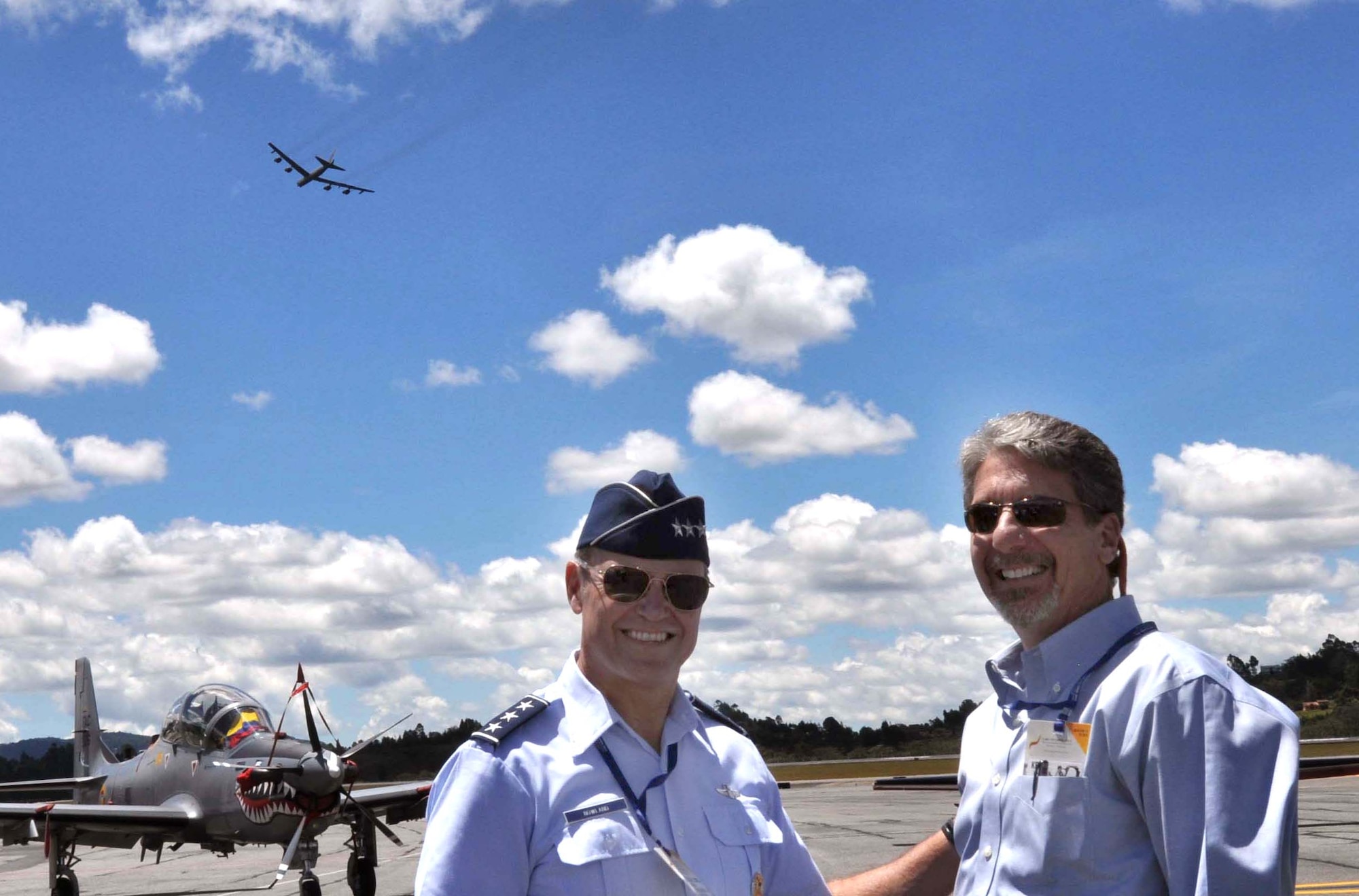 Kevin Whitaker, United States Ambassador to Colombia, poses with Lt. Gen. Chris Nowland, Commander 12th Air Force (Air Forces Southern) as a U.S. Air Force B-52 Stratofortress completes a flyover demonstration at the Colombian International Air Festival, July 9, 2015 in Rionegro, Colombia. The aircraft, which can be seen in the background, took off from its home station at Minot Air Force Base, N.D., to conduct a 16-hour, long-range training mission which included the flyover in Colombia. The B-52 Stratofortress is a long-range strategic aircraft capable of traveling 8,800 miles before refueling. (U.S. Air Force photo by MSgt. Kristina Newton/Released)