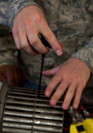 Airman 1st Class Zachery Hatfield, 99th Civil Engineer Squadron heating, ventilation, air conditioning and refrigeration journeyman, removes a part to repair a fan at the 99th CES compound on Nellis Air Force Base, Nev., July 8, 2015. This fan helps move the air around the inside of a building to keep the dorm occupants comfortable. (U.S. Air Force photo by Airman 1st Class Mikaley Towle)