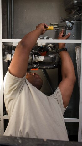 Tech. Sgt. Michael Anderson, 99th Civil Engineer Squadron heating, ventilation, air conditioning and refrigeration craftsman, works to remove an A/C filter at the Nellis Inn on Nellis Air Force Base, Nev., July 8, 2015. Filters are changed regularly as part of preventive maintenance. (U.S. Air Force photo by Airman 1st Class Mikaley Towle)