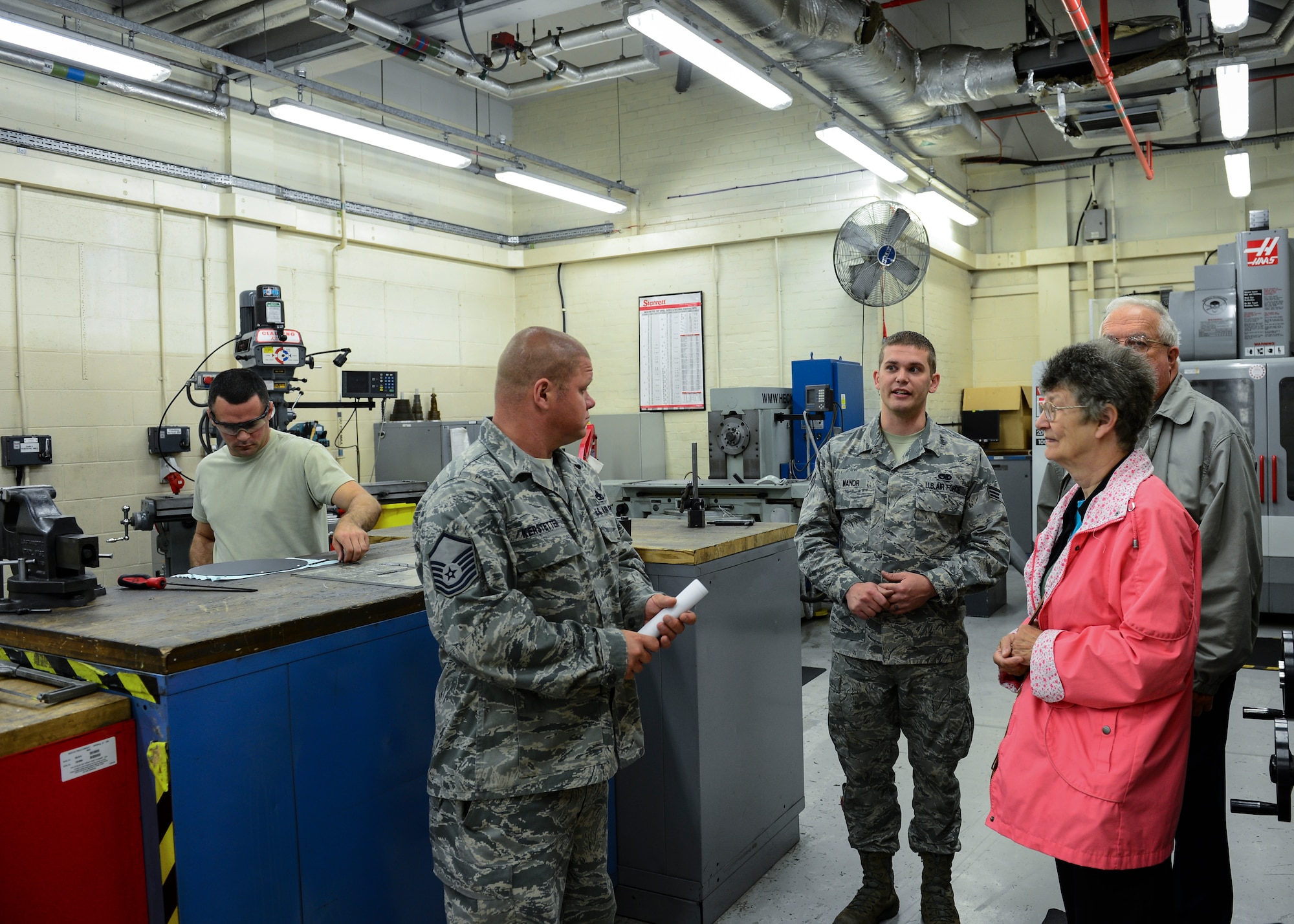 Senior Airman Adam Manor, 48th Equipment Maintenance Squadron metals technology journeyman, gives Robert and Bobbette Fluck a tour through the sheet metal section of Hangar 7 at Royal Air Force Lakenheath, July 7, 2015. Fluck served his first term of enlistment at RAF Lakenheath as a young Airman from 1963-1968 and is one of the oldest members of the EMS squadron. (U.S. Air Force photo by Senior Airman Nigel Sandridge/Released)