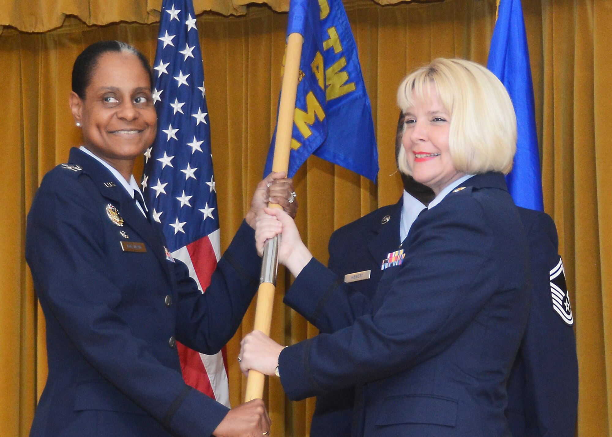 Col. Karen Cox-Dean (left), 412th Medical Group commander, and new 412th Aerospace Medicine Squadron commander, Maj. Angela Albrecht, pose for a photo with the 412th AMDS guidon July 9 at Club Muroc. Albrecht assumed command of the squadron from outgoing commander Lt. Col. Patricia MacSparran. (U.S. Air Force photo by Patric Lovato)