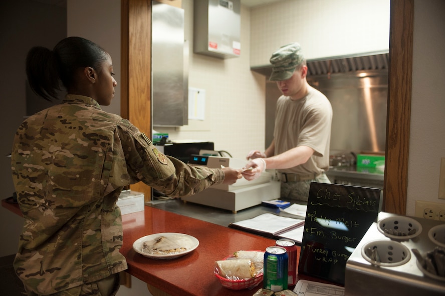 Staff Sgt. Ryan Patriok, 5th Force Support Squadron missile chef, hands change for a meal back to Senior Airman Sierra Jackson, 91st Missile Security Forces Squadron fire team member, at the Bravo 01 Missile Alert Facility, July 1, 2015. Missile chefs work an average of 10 hours a day but may work up to 17 hours depending on the needs of personnel staying at the MAF. (U.S. Air Force photo/Senior Airman Stephanie Morris)