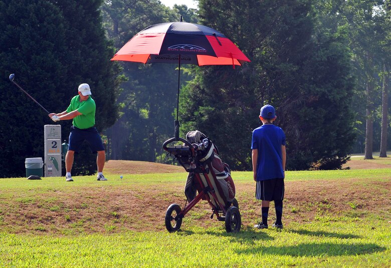 Jeff Dahlinger, a retiree, enjoys a morning of golf at Pine Oaks as 8 year-old acting caddy, Garett Rogers, looks on. The 18-hole course at Robins features 6,343 yards of golf from the longest tees for a par of 71. (U.S. Air Force photo by Tommie Horton)