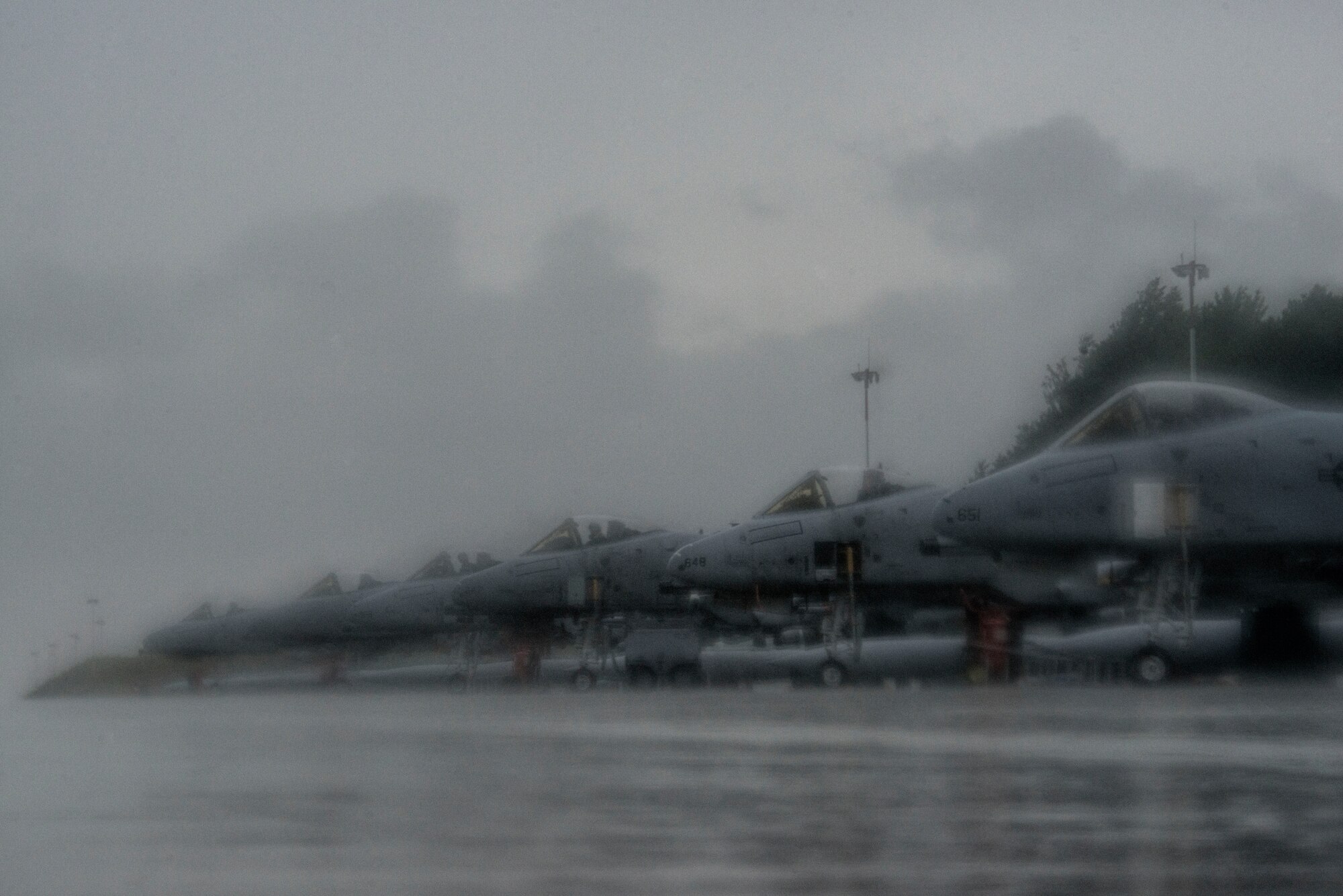 Rain comes down as U.S. Air Force Airmen assigned to the 354th Expeditionary Fighter Squadron prep three U.S. Air Force A-10 Thunderbolt II attack aircraft for flight during a theater security package deployment to Lask Air Base, Poland, July 9, 2015. U.S. Air Force Airmen and support equipment from the 355th Fighter Wing at Davis-Monthan Air Force Base, Ariz., and the 52nd Fighter Wing at Spangdahlem Air Base, Germany, will support this deployment. (U.S. Air Force photo by Staff Sgt. Christopher Ruano/Released)