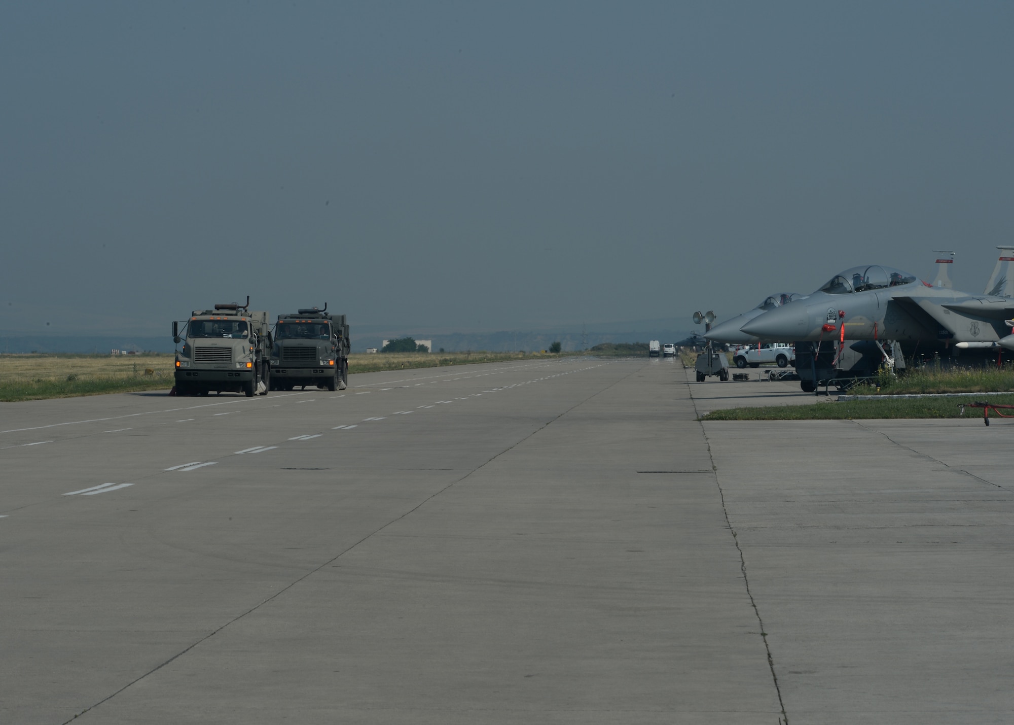 Two U.S. Air Force air field sweepers taxi on the flightline after completing a sweeping operation during a theater security package July 8, 2015, at Campia Turzii, Romania. Civil engineer Airmen perform daily sweeping operations to ensure foreign objects are clear from the flightline. (U.S. Air Force photo by Senior Airman Dylan Nuckolls/Released)