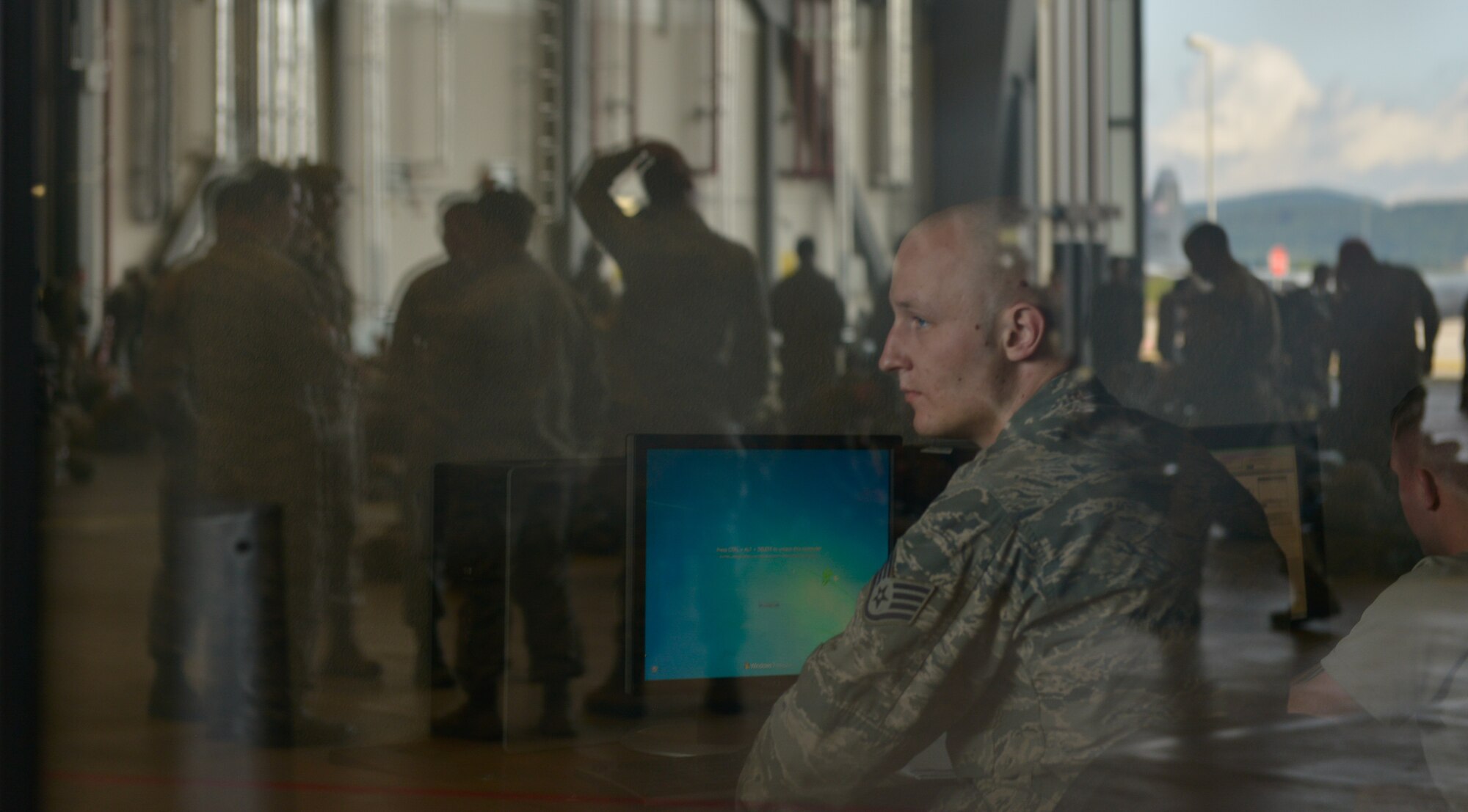 Staff Sgt. Steven Nordhoff, 86th Aircraft Maintenance Squadron aerospace propulsion craftsman, takes a quick break from work to observe the crowd waiting to jump during International Jump Week July 9, 2015, at Ramstein Air Base. U.S. Air Force and Army service members worked alongside nine allied countries’ militaries to increase interoperability and strengthen partnerships. (U.S. Air Force photo/Airman 1st Class Lane T. Plummer)