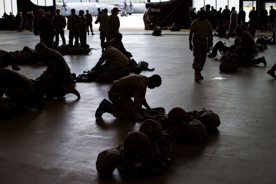 Service members pack parachutes prior to jumping during International Jump Week, July 8, 2015 at Ramstein Air Base, Germany. International Jump Week is an annual event providing paratroopers the opportunity to practice high altitude, low opening and static-line jumps. Pilots, loadmasters and parachute riggers were also able to train during the week. Supporting units at the drop zone included U.S. Air Force and Army personnel, air traffic controllers and medical teams. (U.S. Air Force photo/Senior Airman Damon Kasberg)