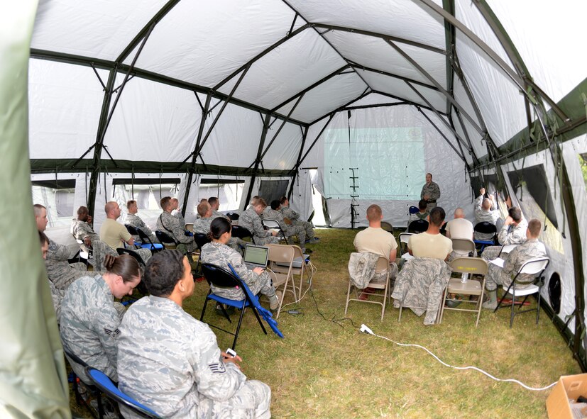 U.S. Air Force Senior Airman Logan Fountaine, standing, 100th Civil Engineer Squadron Engineering journeyman from Ontario, N.Y., instructs a land navigation course during the 100th CES bivouac training June 25, 2015, on RAF Mildenhall, England. The course focuses on survival techniques including how to read topographical maps, using a lensatic compass, and how to read and plot military grid reference system coordinates. (U.S. Air Force photo by Karen Abeyasekere/Released)