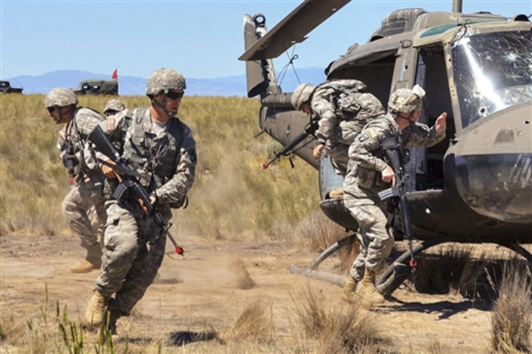 Washington National Guard soldiers dismount a UH-1H helicopter and take up defensive fighting positions during predeployment training at the Yakima Training Center, Wash., June 20, 2015. The soldiers are assigned to the Guard's 1st Battalion, 168th General Support Aviation Battalion.