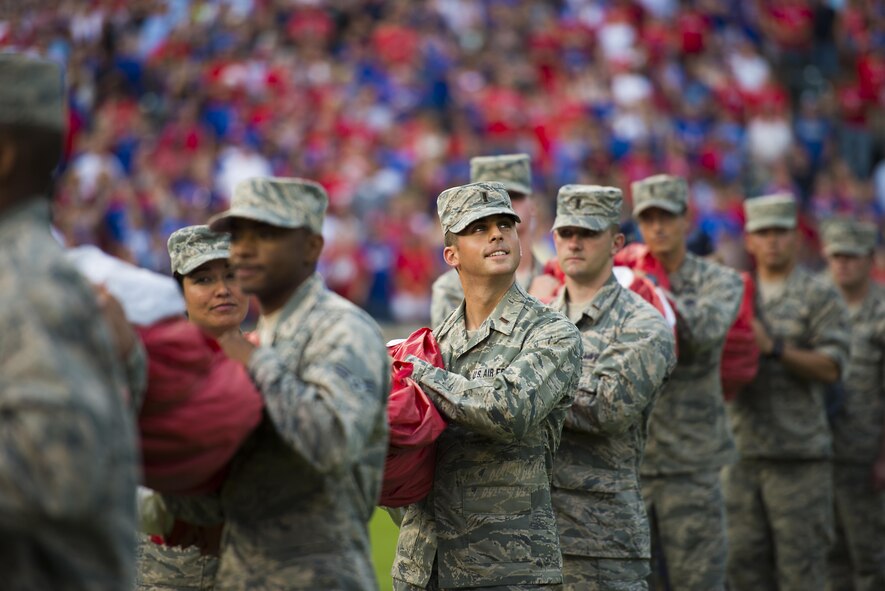U.S. Air Force 2nd Lt. Tyler Almquist, student at Sheppard Air Force Base, Texas, helps hold a giant U.S. Flag for an enlistment ceremony during the opening of the Rangers game in Arlington, Texas, July 4, 2015. More than 60 Airmen from Sheppard volunteered with the 344th Recruiting Squadron to help unfurl the flag for approximately 150 new Air Force enlistees who swore-in during the game. (U.S. Air Force photo by Senior Airman Kyle Gese)